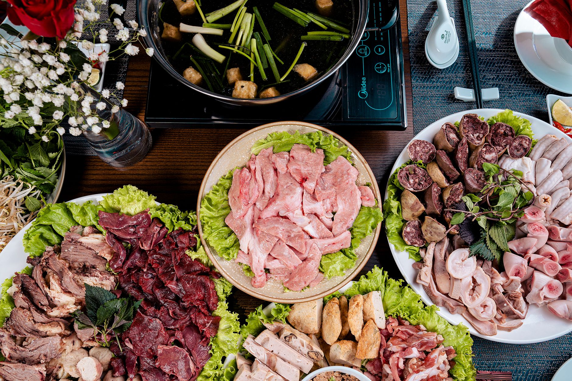 Guests seated around a hotpot table with shared broth and plates during a busy dinner service.