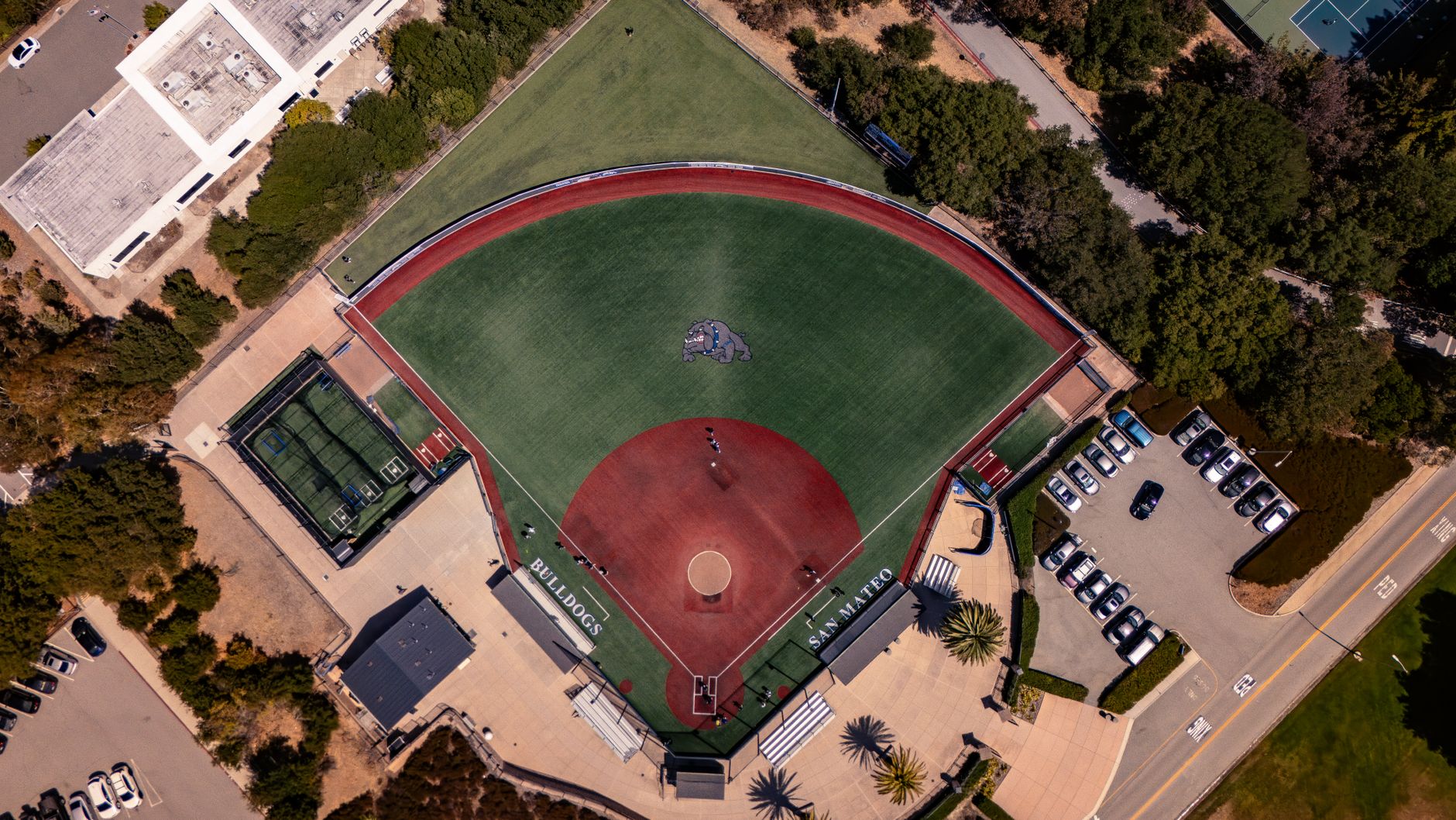 Wide green athletic turf at a public school campus on a clear day.