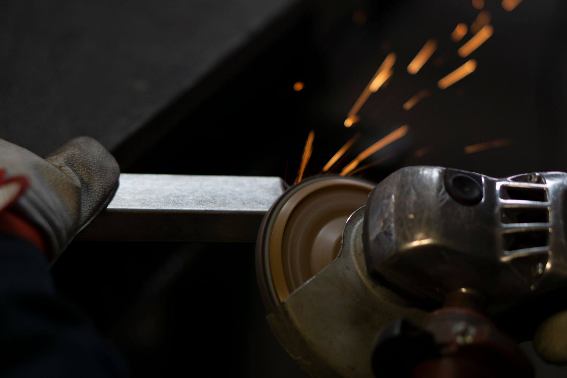 A technician grinds a welded seam on a metal assembly at a workbench.