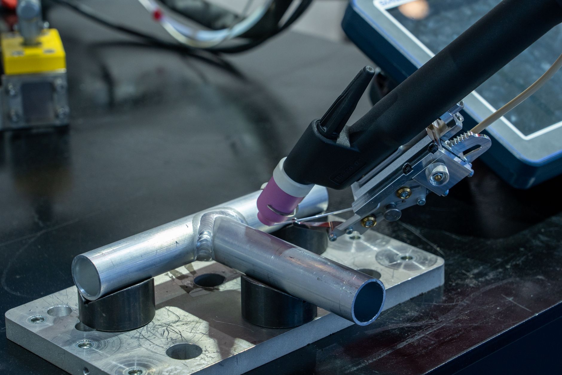A close view of a skilled welder making a precise TIG weld on an aluminum assembly.