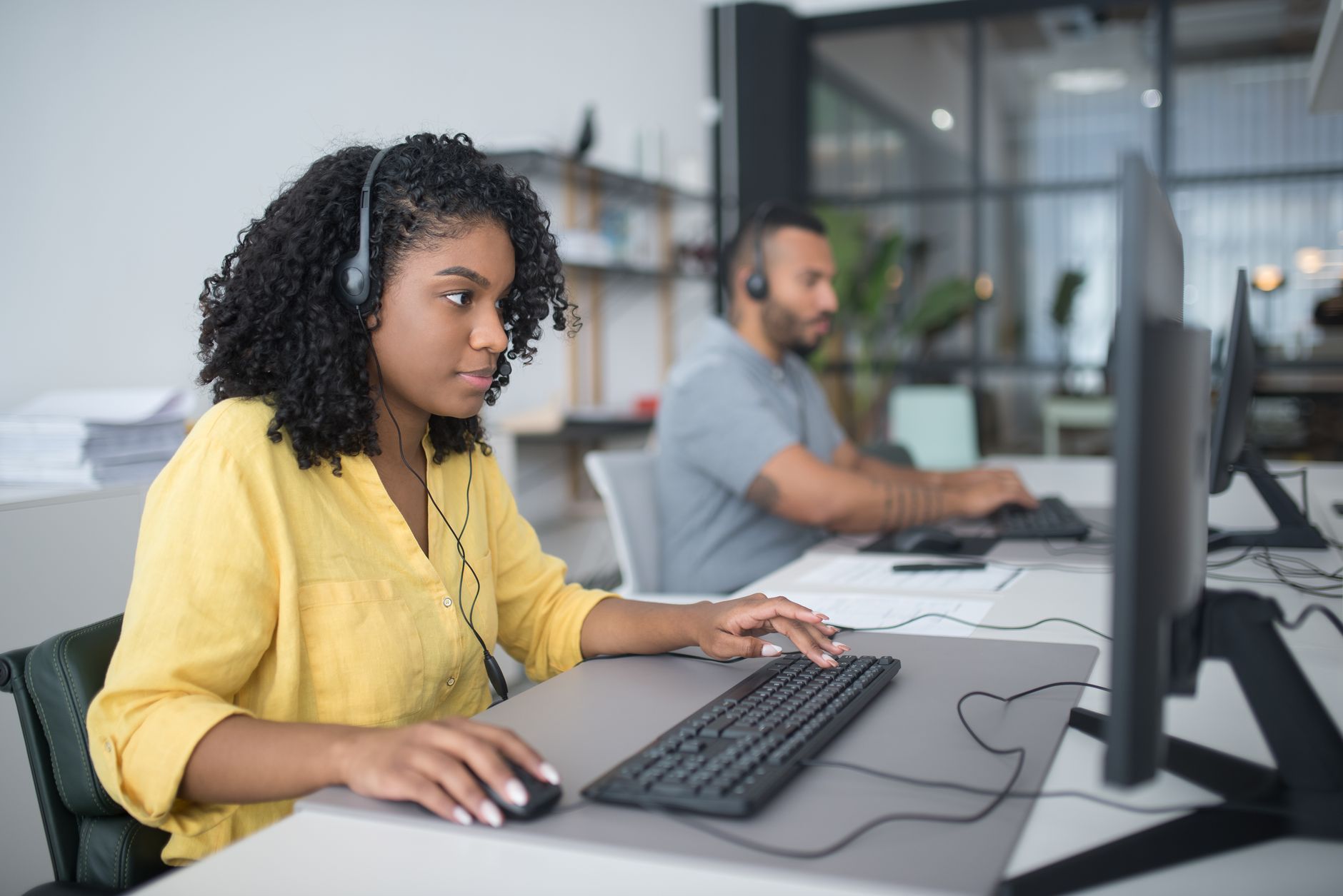 Call-center employees work at desks beside the warehouse operation.