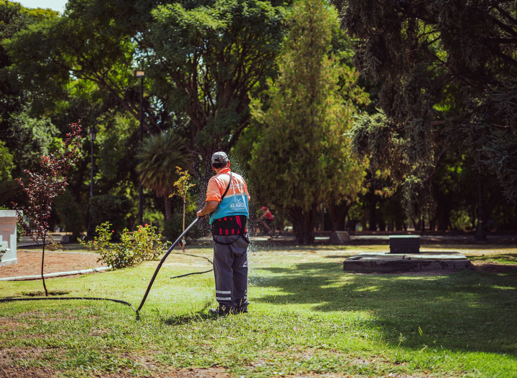 A parks worker tending turf and landscaping tasks away from the main mowing route.