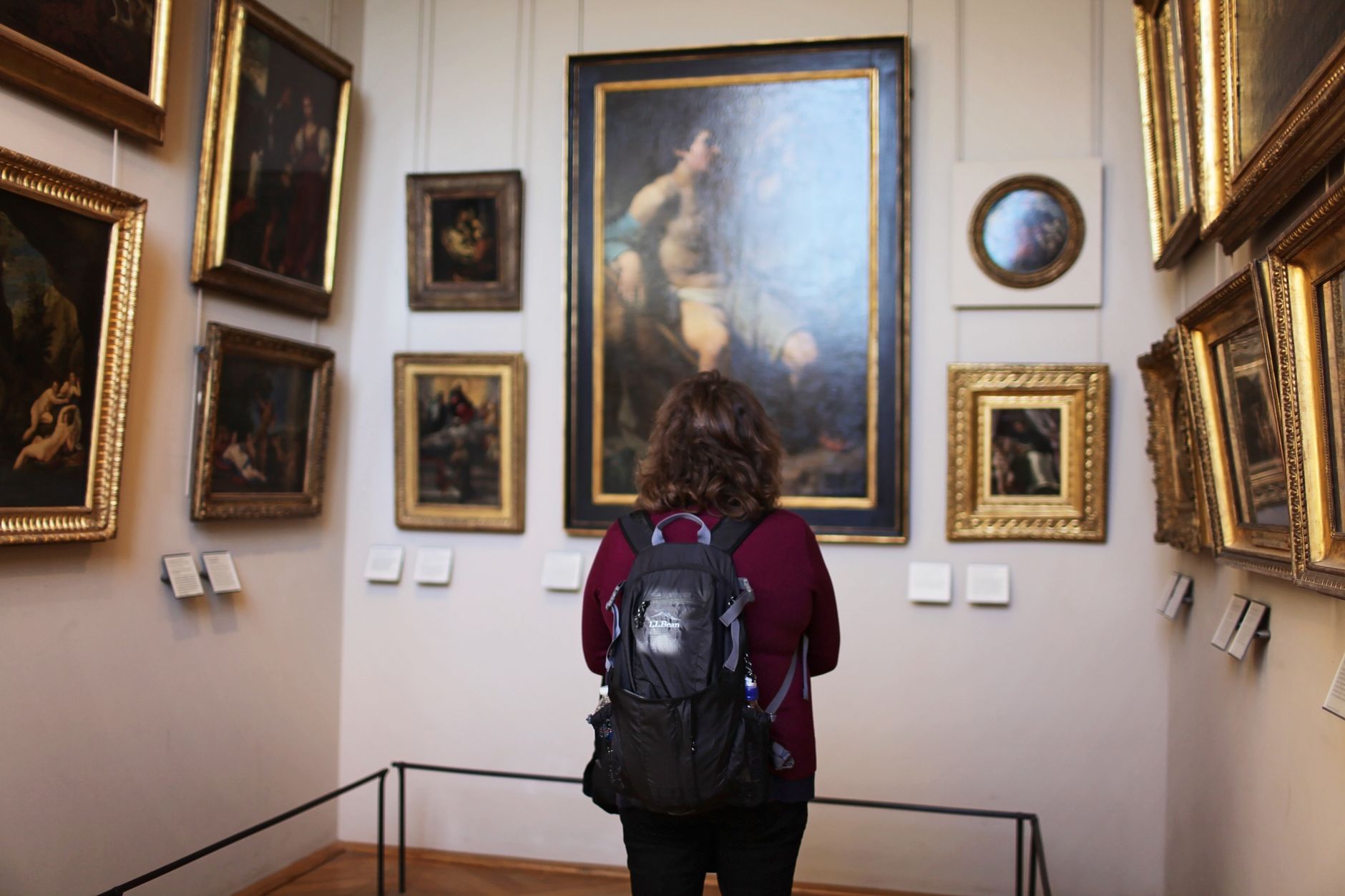 A museum visitor listens to interpretive guidance while studying an exhibit.