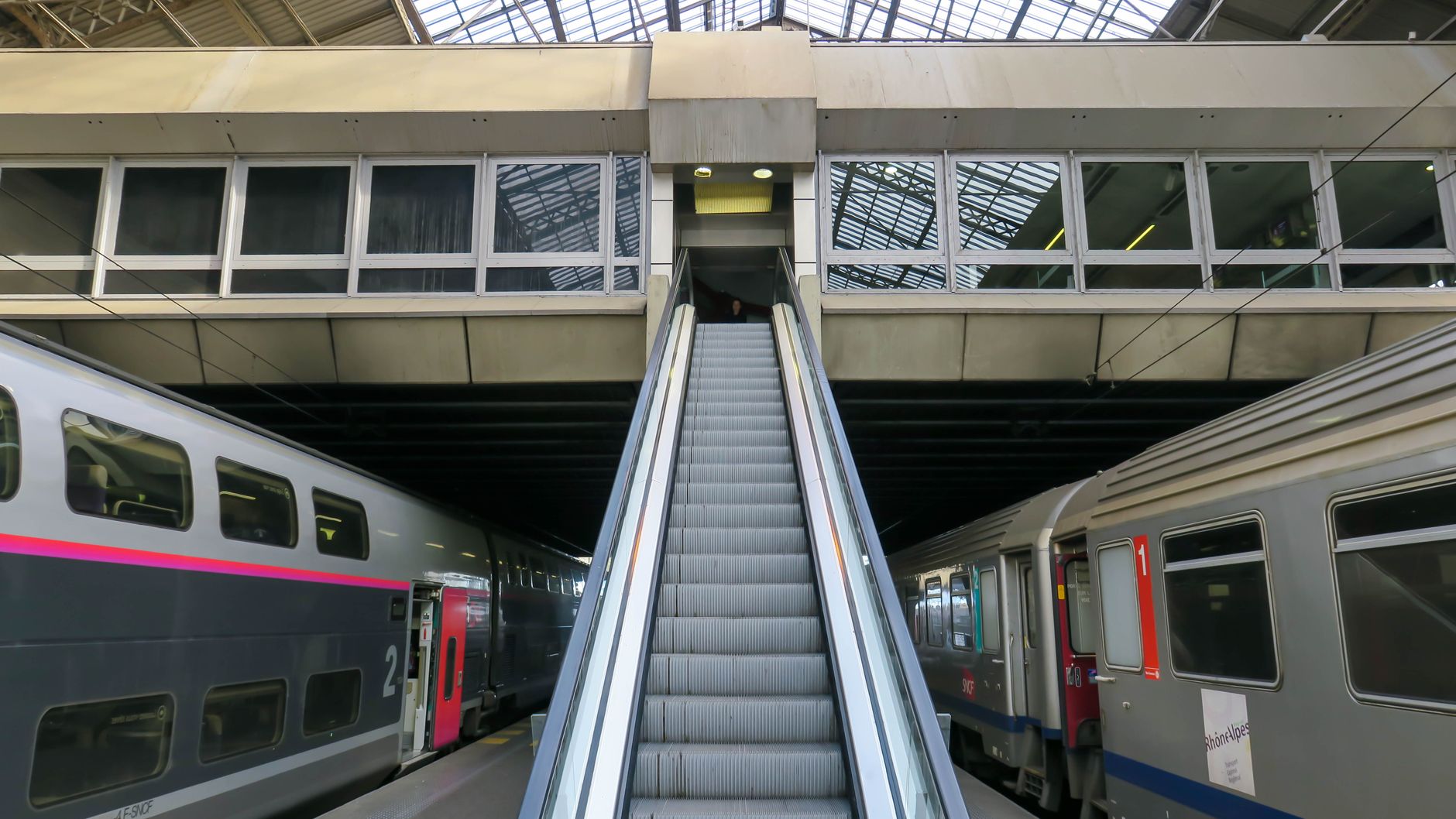 Passengers cross a bright railway concourse with polished floors and high ceilings.