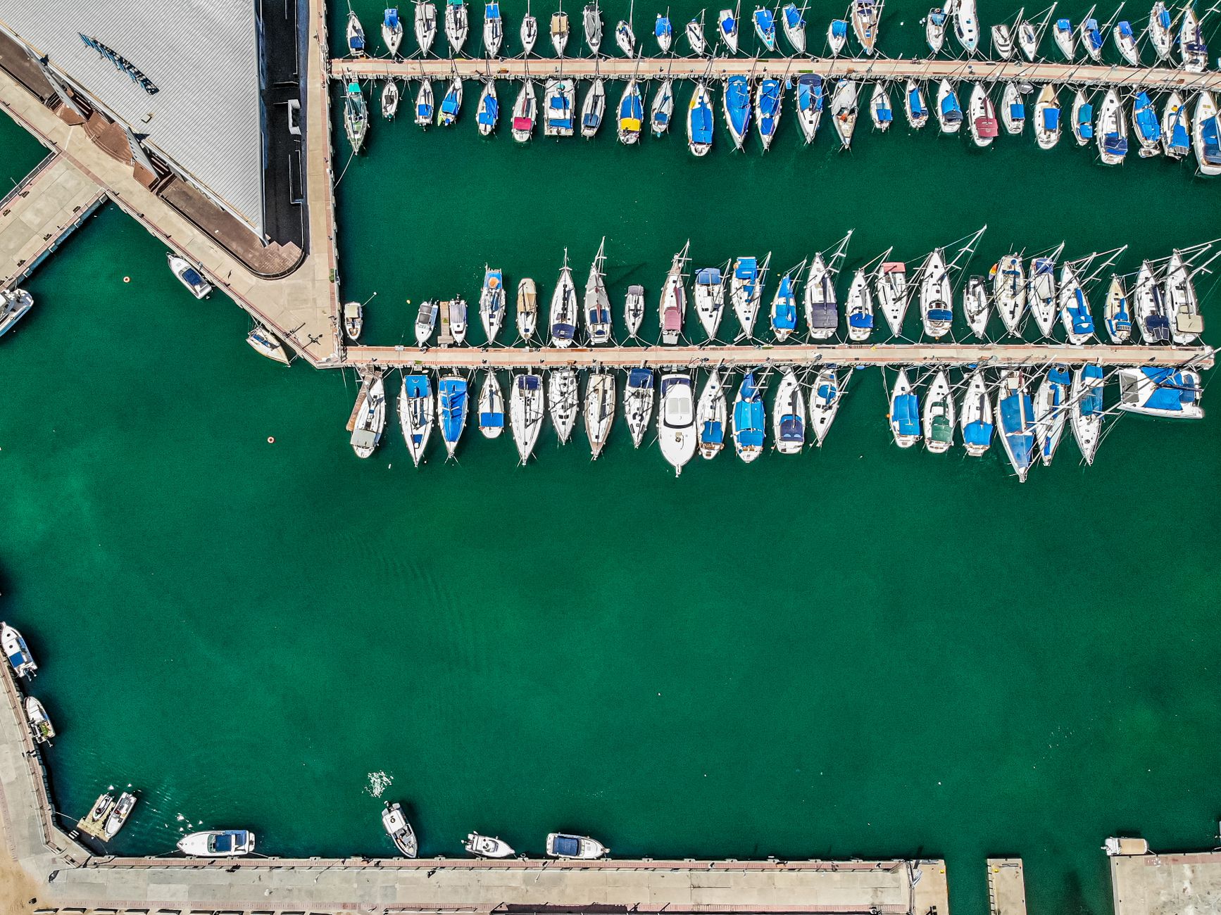 Aerial view of a crowded island marina with sailboats tied along floating docks.