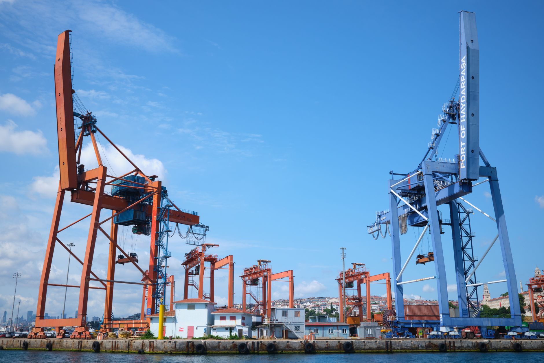 Industrial waterfront with piers and cargo equipment under a clear sky.