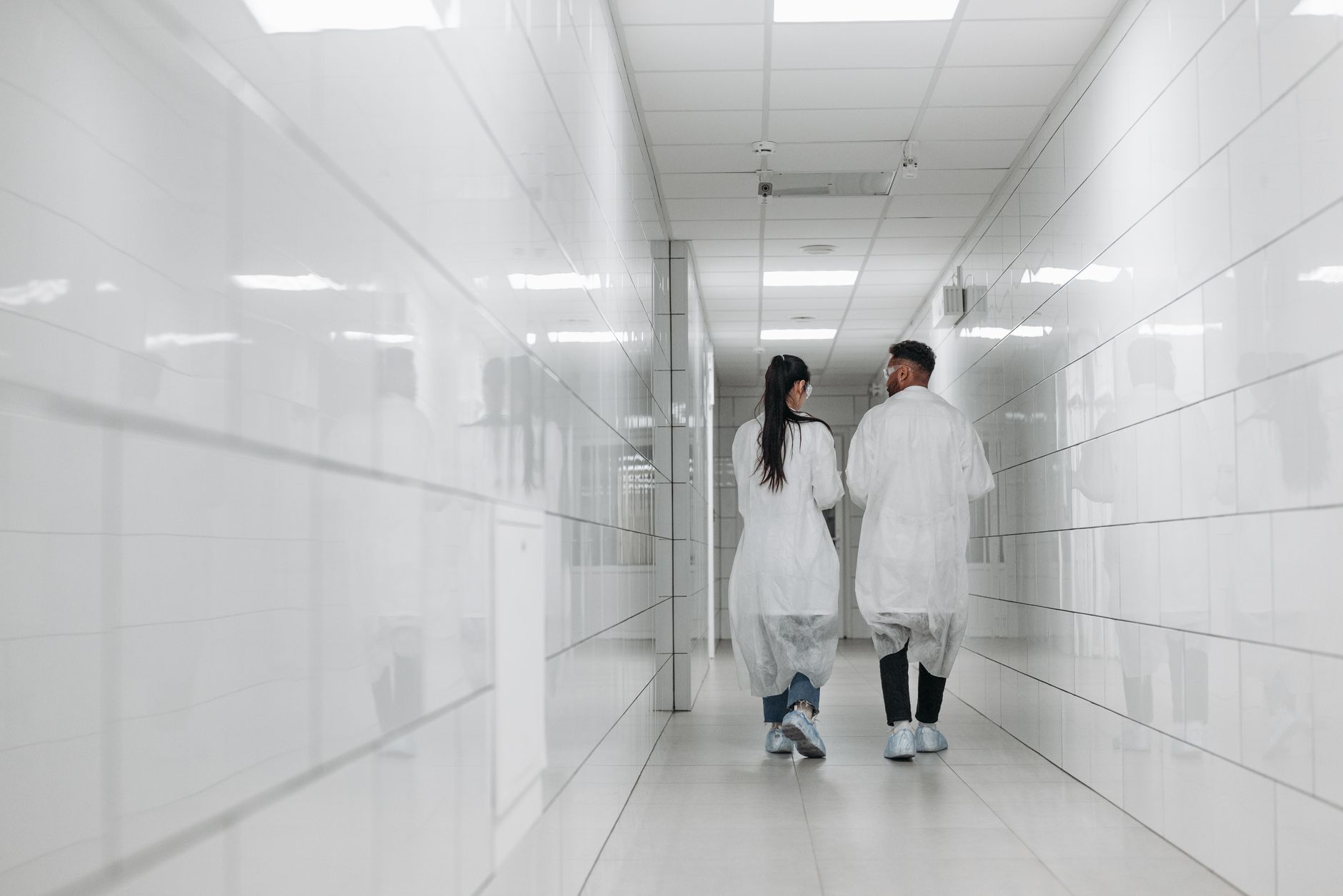 A long, brightly lit pharmaceutical corridor where maintenance cleaning must stay on schedule overnight.