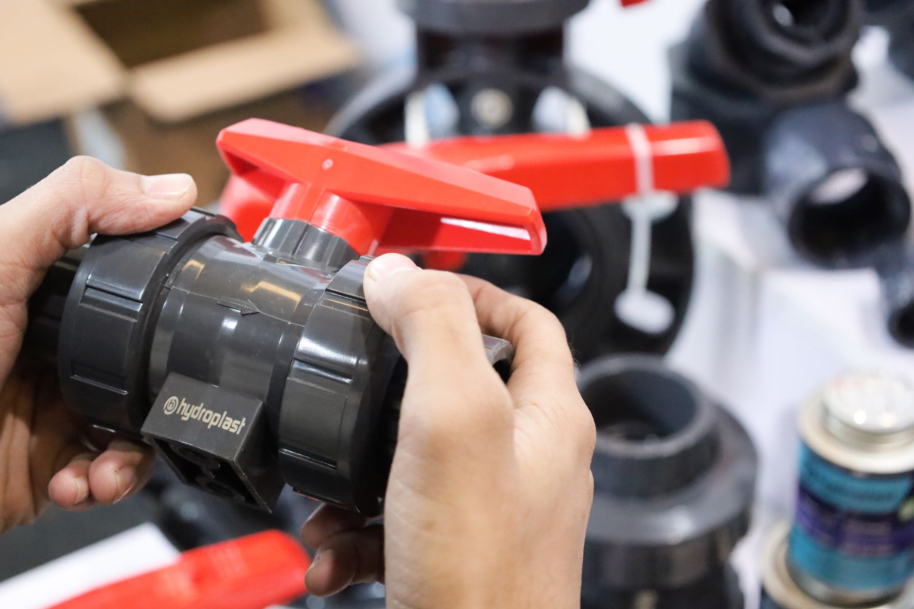 Worker inspecting freshly molded plastic parts at a manufacturing bench, reflecting the quality pressures inside a small injection molding plant.