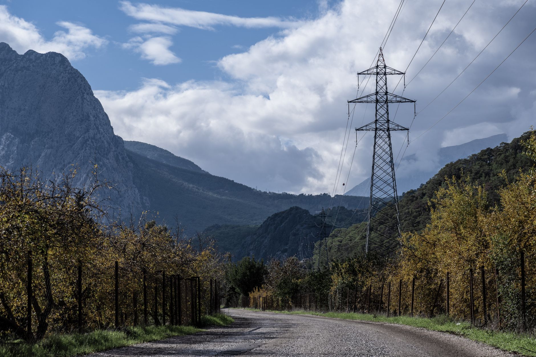 High-voltage transmission lines crossing steep, forested mountain ridges.