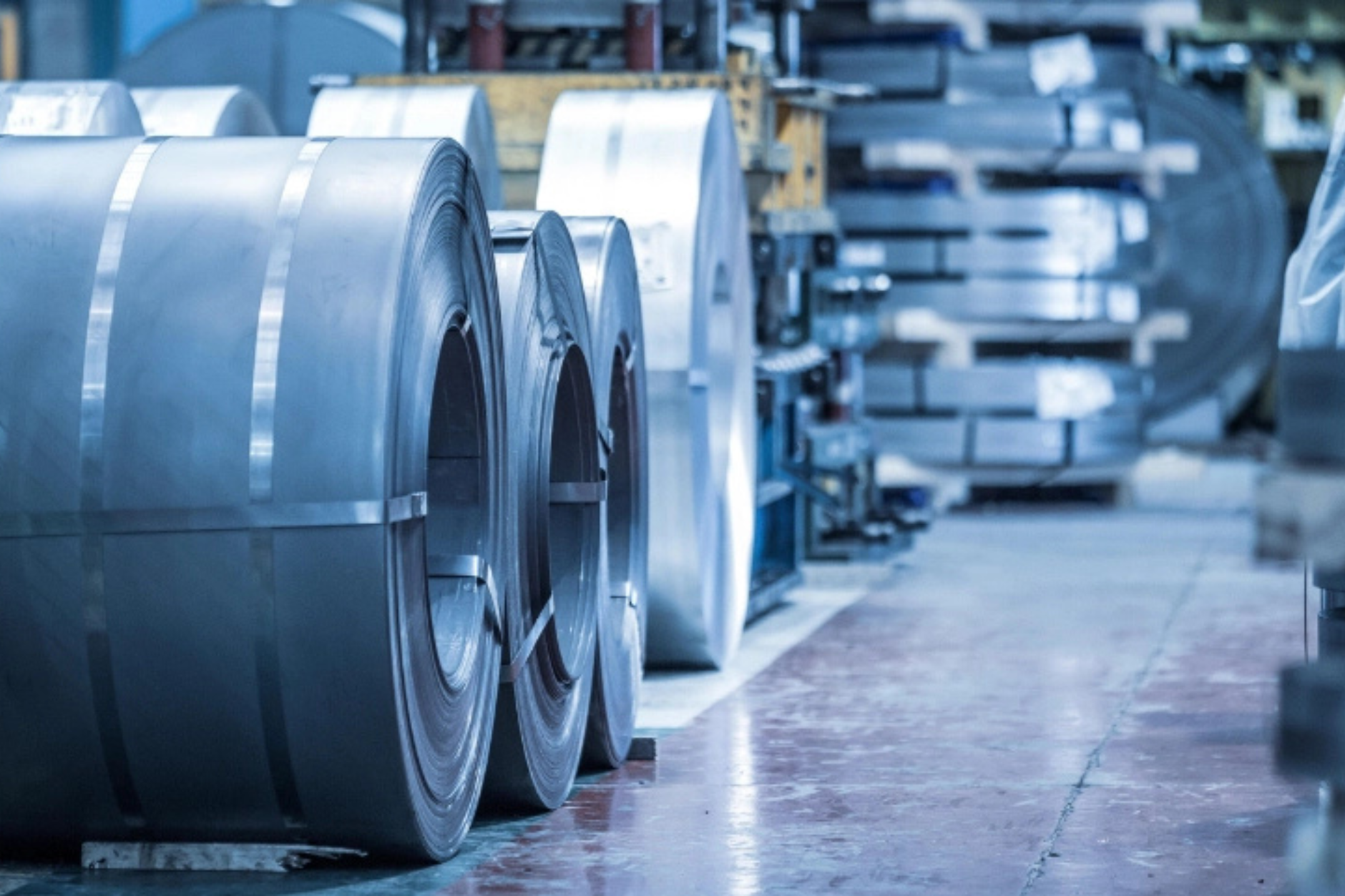 Wide view of a precision sheet-metal factory floor with long aisles and active work areas where dust-prone cleaning would matter at shift change.
