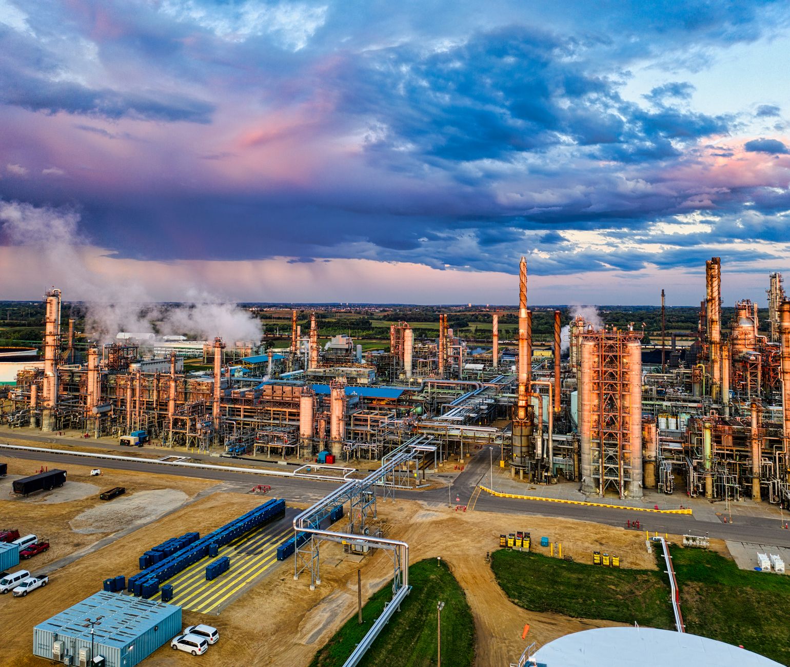 Operators monitoring refinery processes from an industrial control room while the fuel tank remains in service.