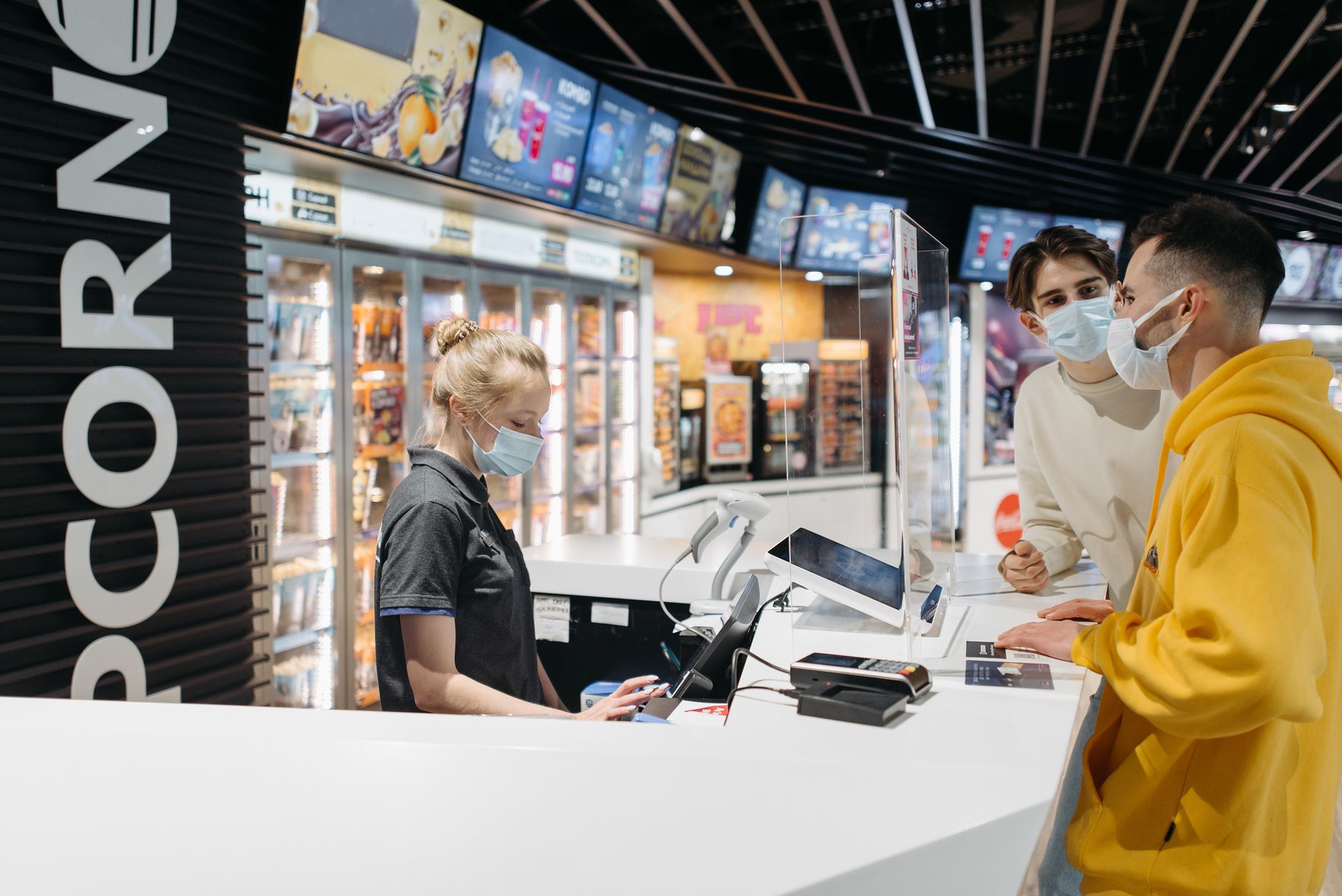 Concession staff serving moviegoers at a busy theater snack counter.
