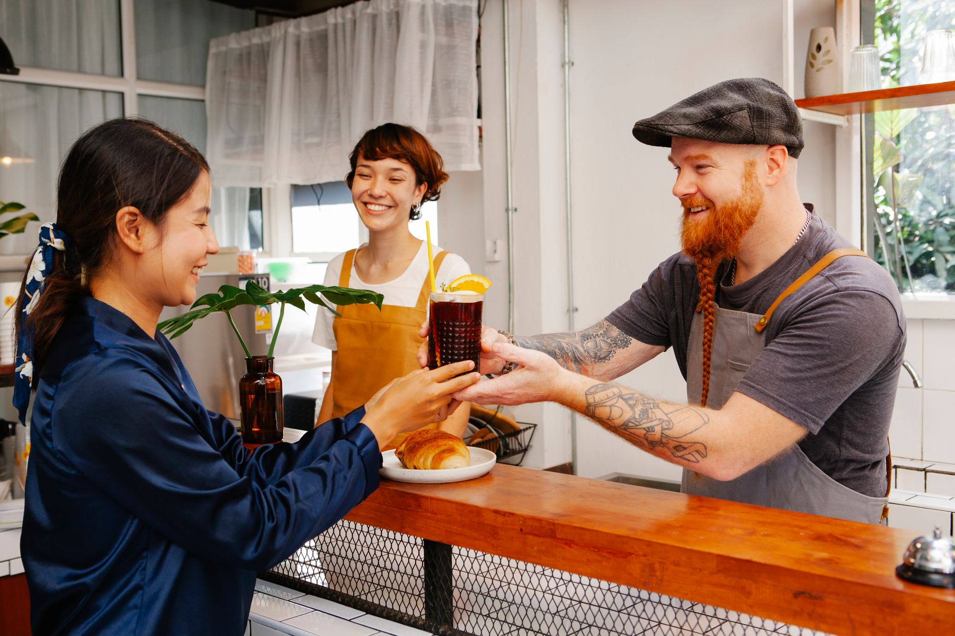 Cafe staff engage with guests across a welcoming service counter.