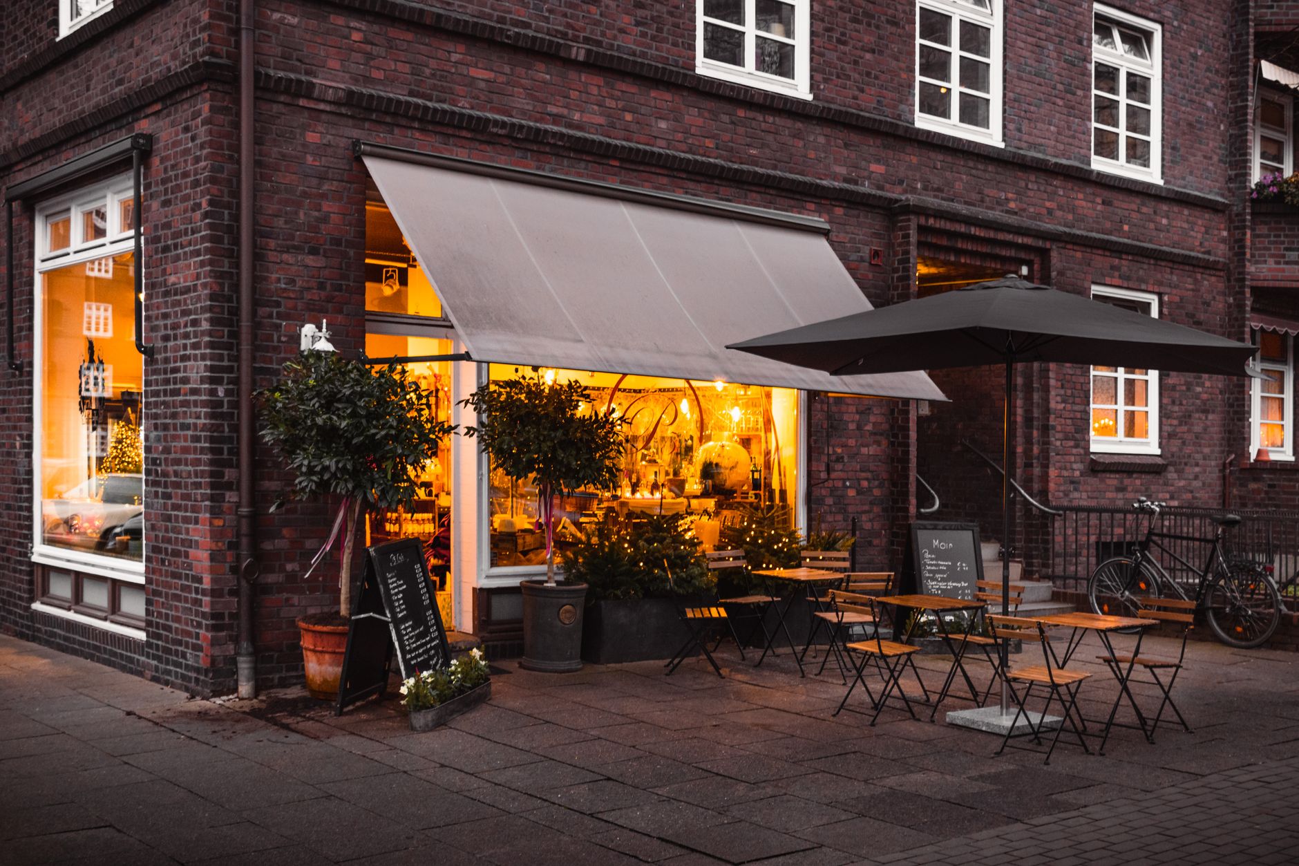 An inviting cafe storefront with outdoor seating in a busy retail center.