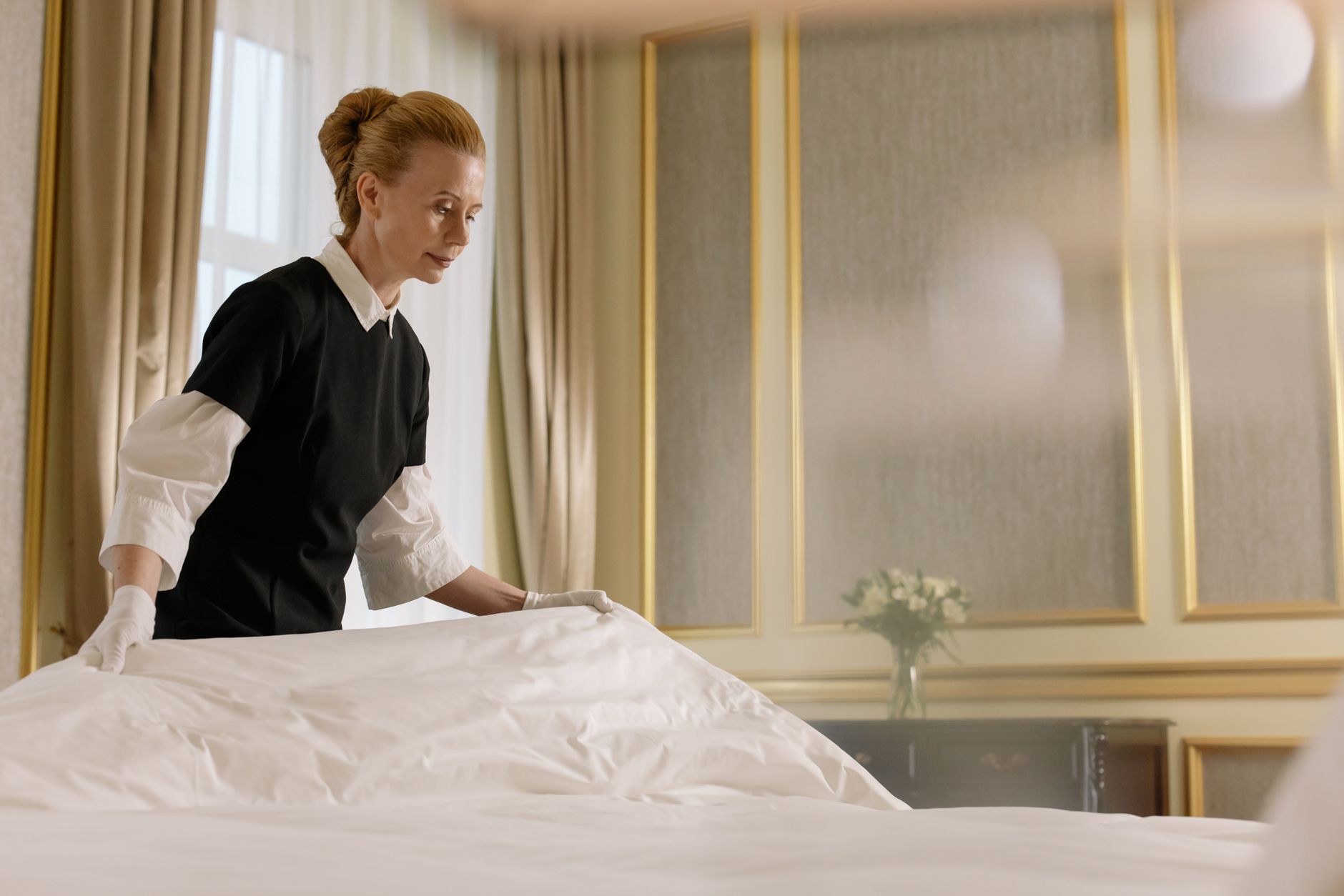 A hotel employee preparing a guest room reflects the hands-on service work that still requires reliable human attention.