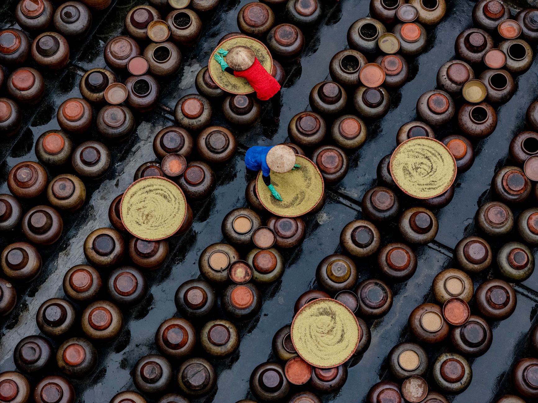 Workers prepare ingredients in a stainless-steel sauce production kitchen.