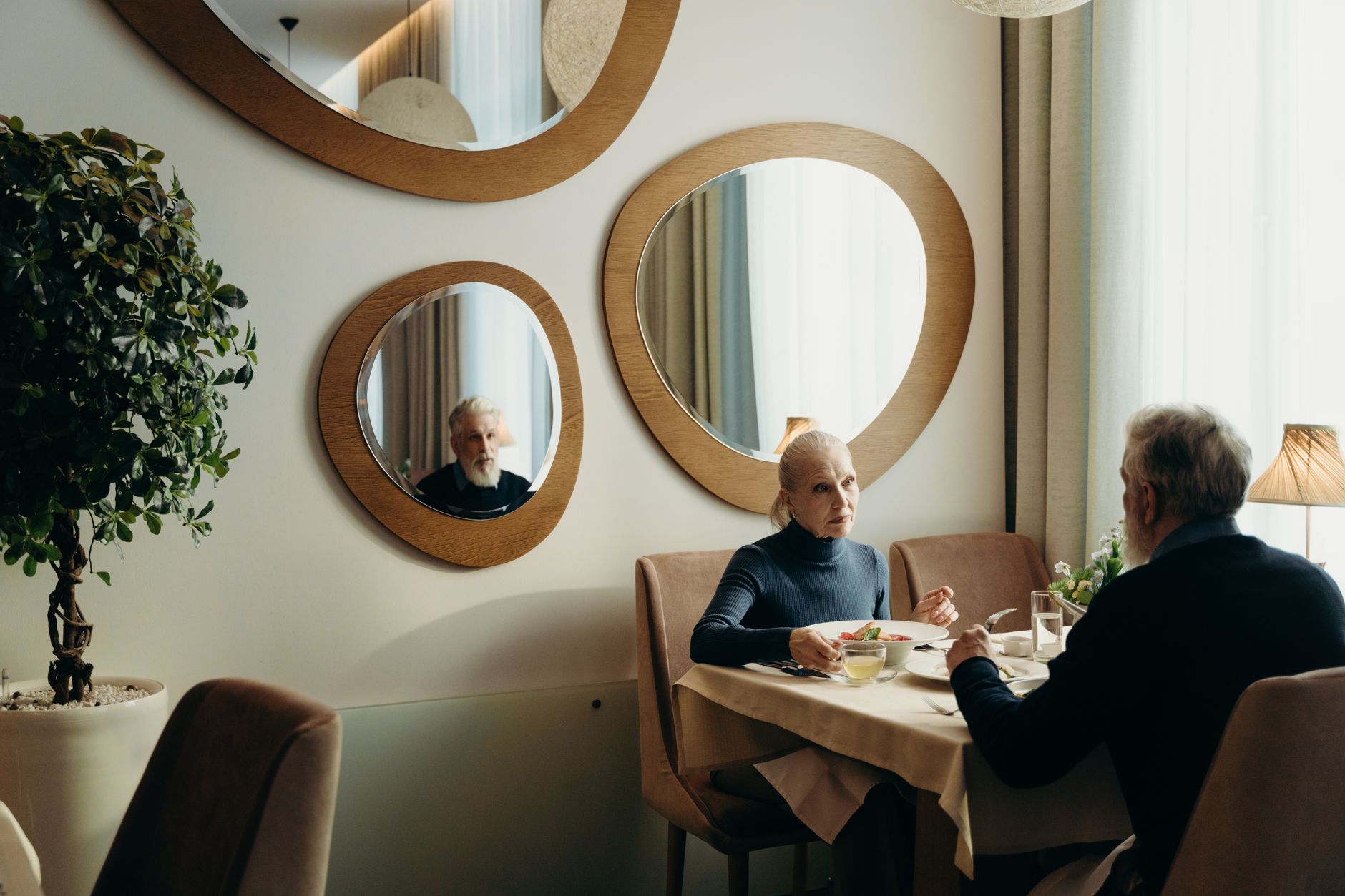 A welcoming dining area in a continuing care campus with natural light and place settings ready for residents.