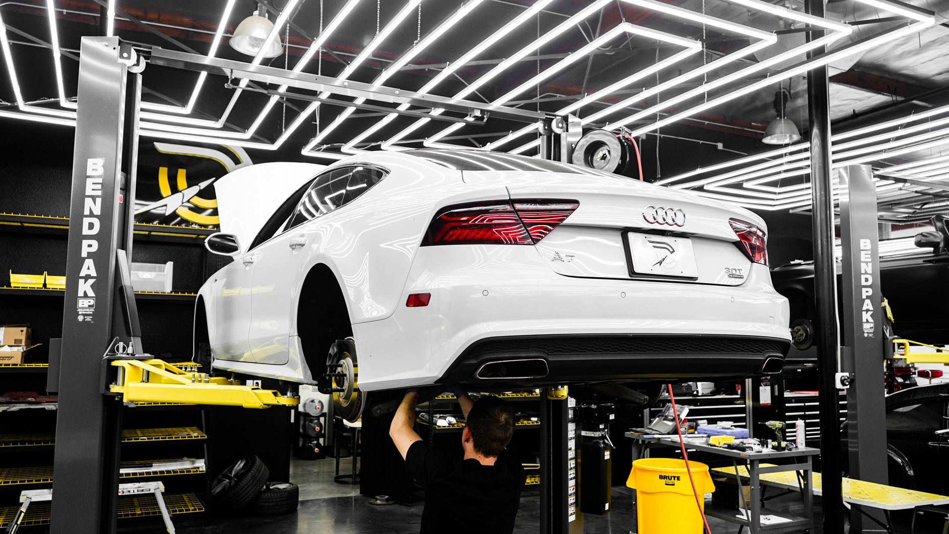 Technicians work across active vehicle lifts in a high-throughput dealership service department.