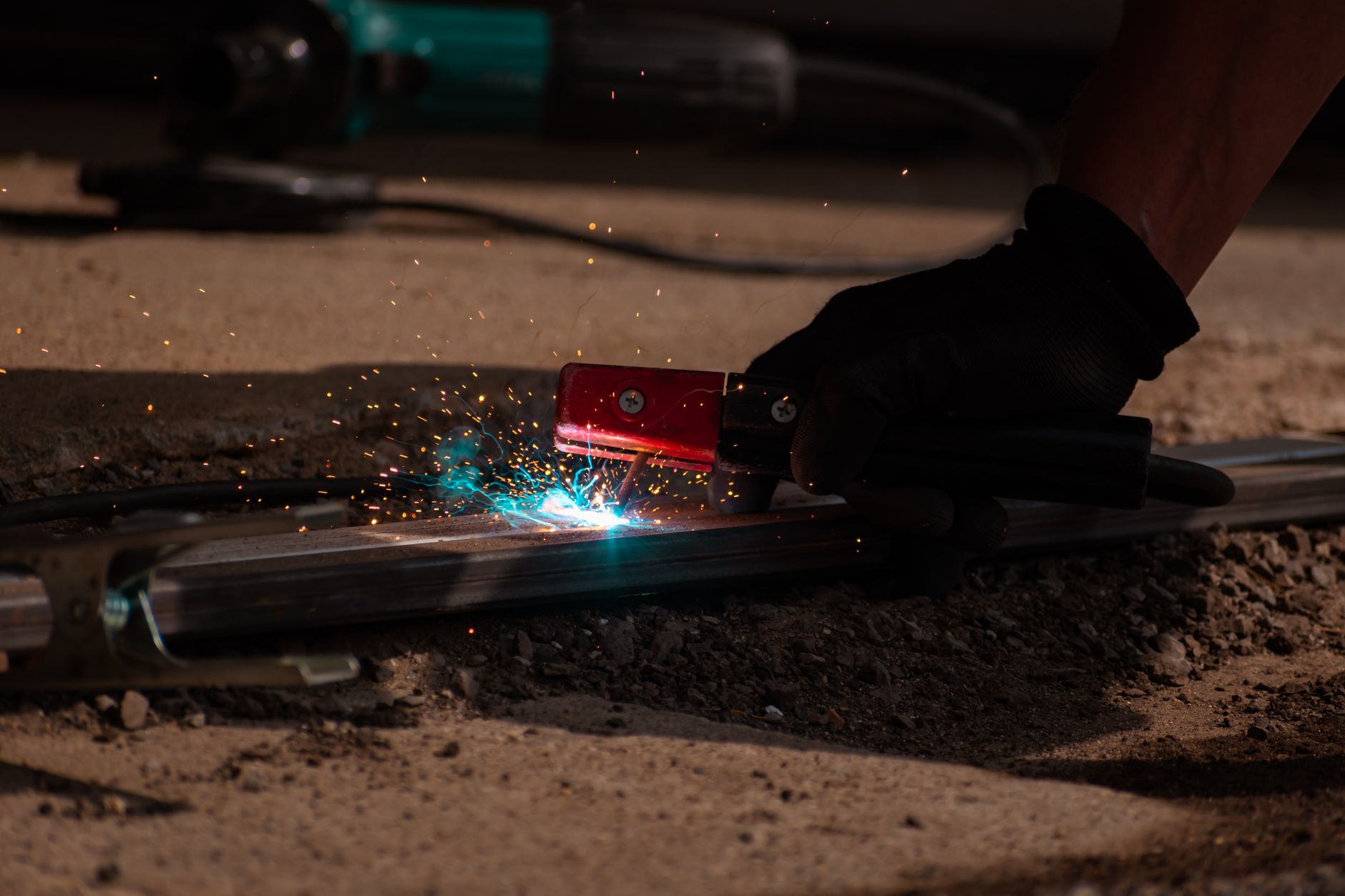 A close view of a worker guiding a welding torch along a metal joint.