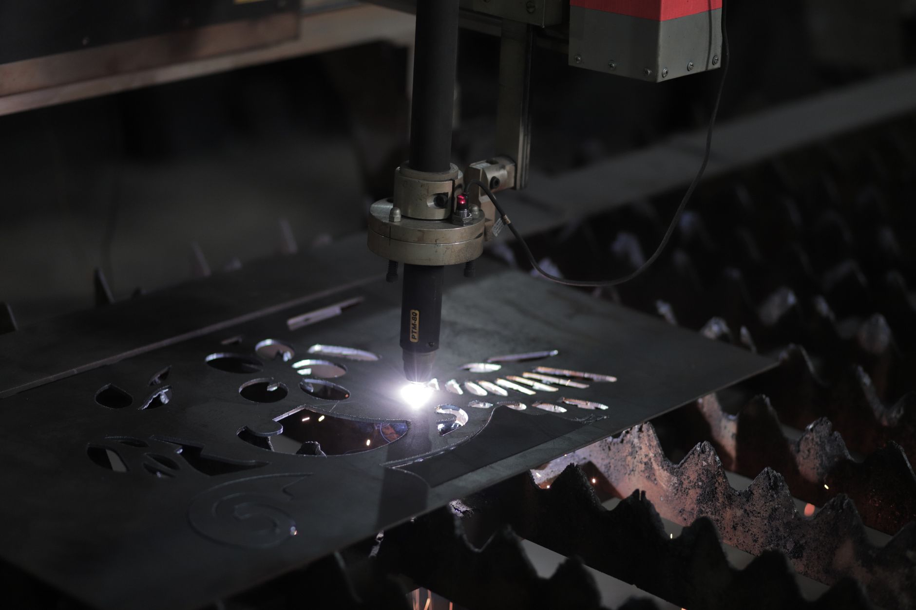 A worker handling sheet metal inside a compact fabrication workshop.