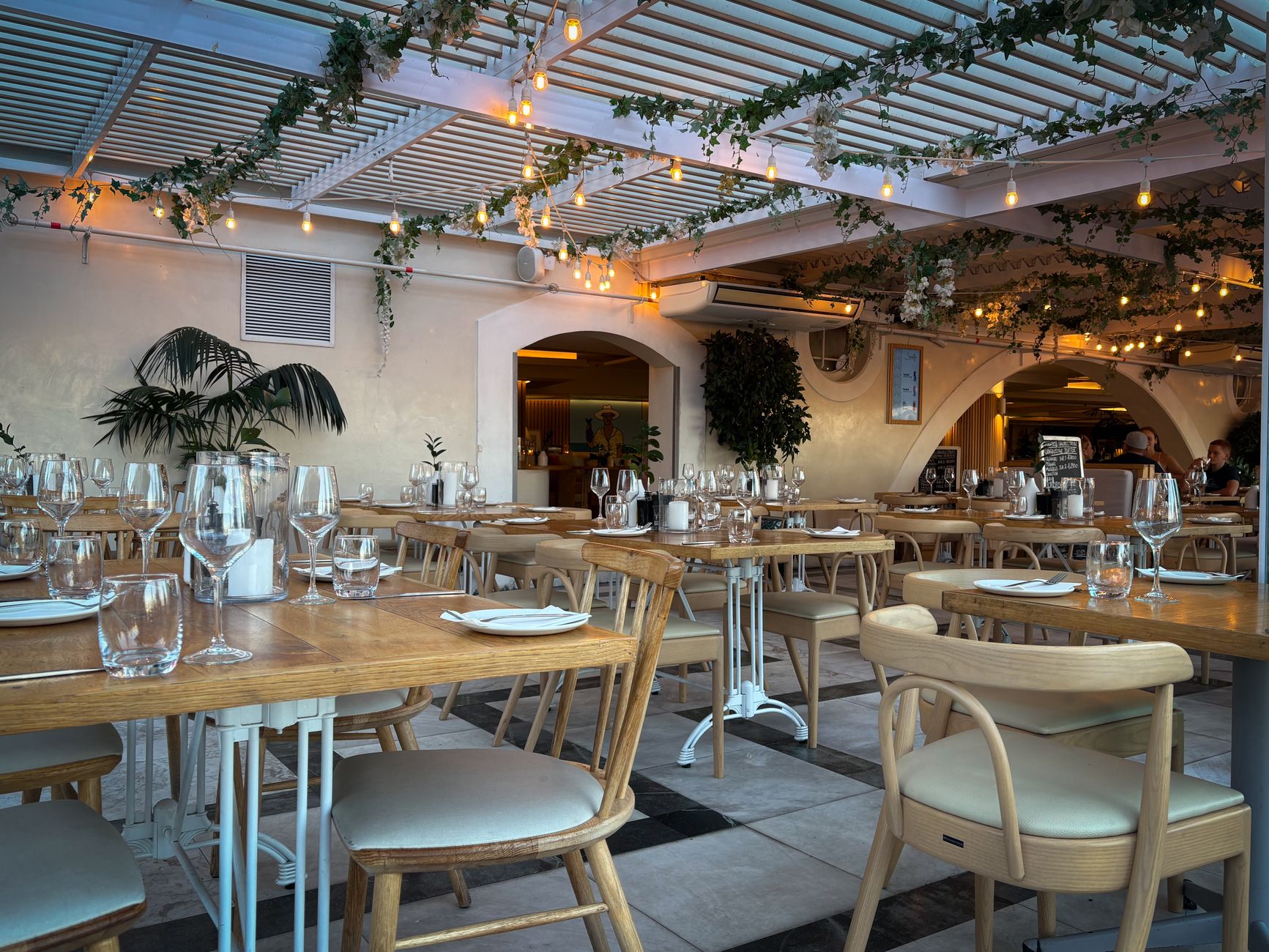 A wide restaurant dining room filled with tables ready for lunch service.