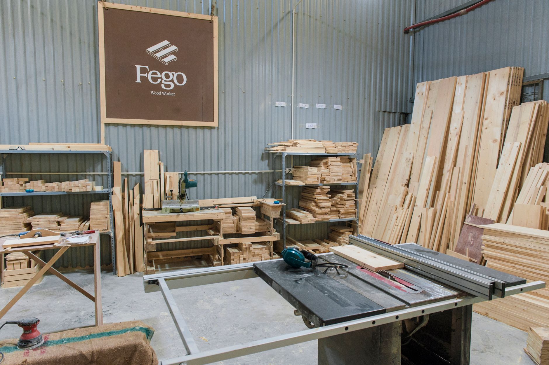 Warm light across a woodworking shop where finished wood panels wait on benches.