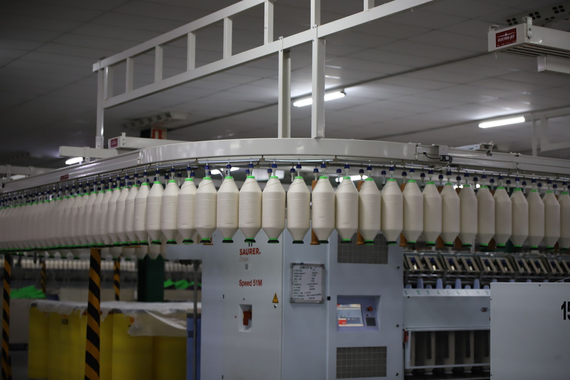 Workers sew white bedding products inside a bright, orderly textile manufacturing facility.