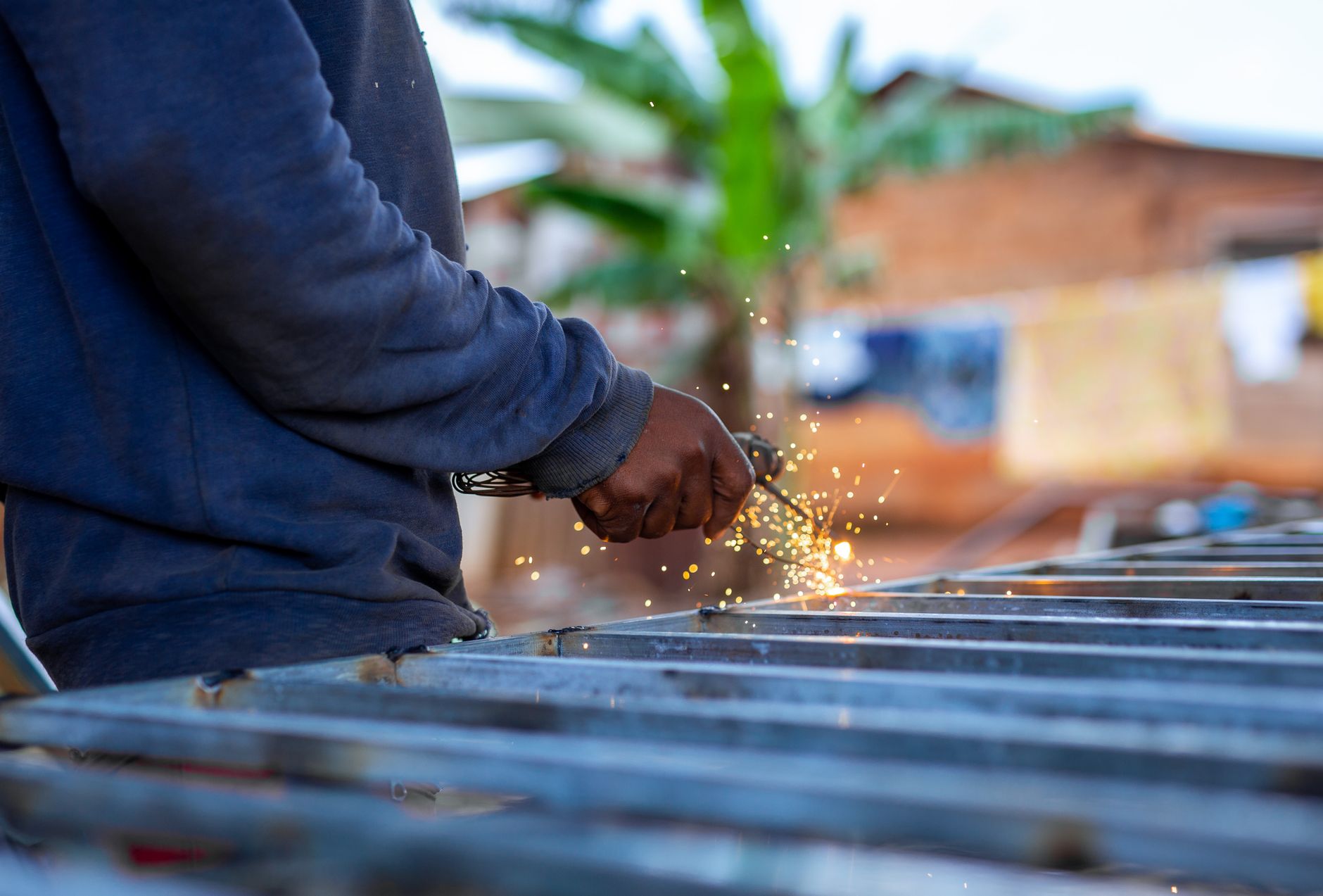 A welder works inside a rural metal fabrication shop like the facility producing solar mounting components.
