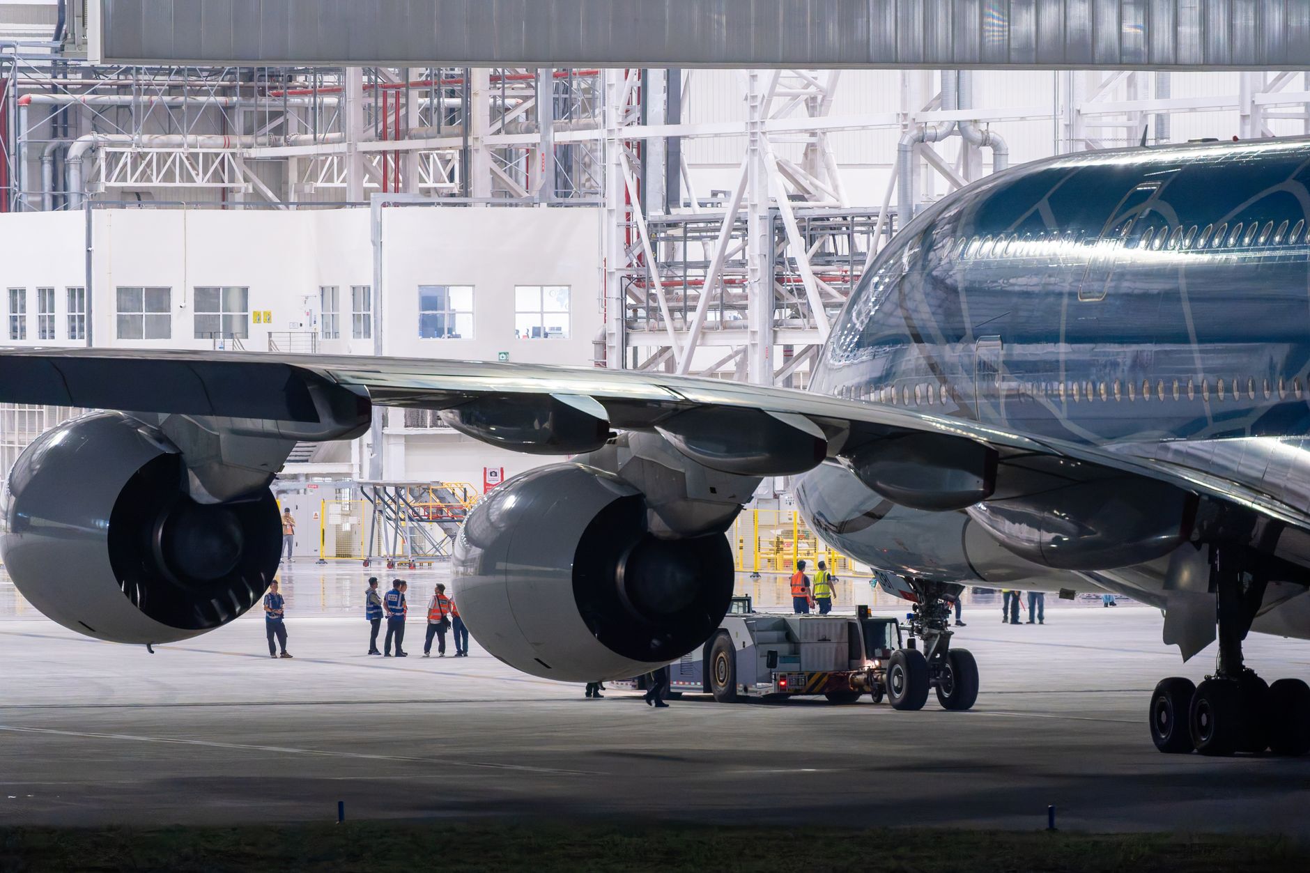 Technicians work near an aircraft wing during a manual maintenance check.