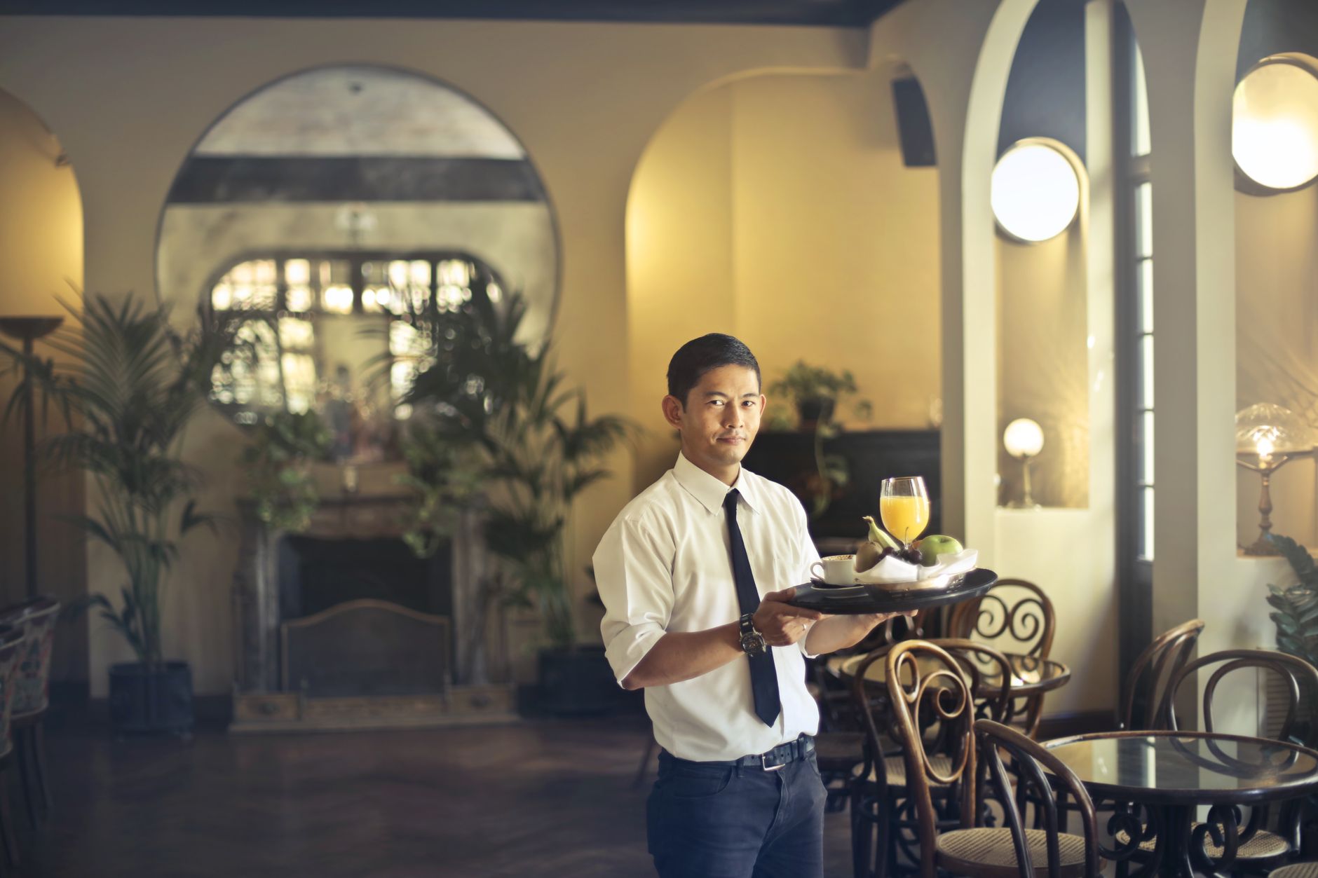 Hotel restaurant staff carrying trays through a busy buffet dining area.