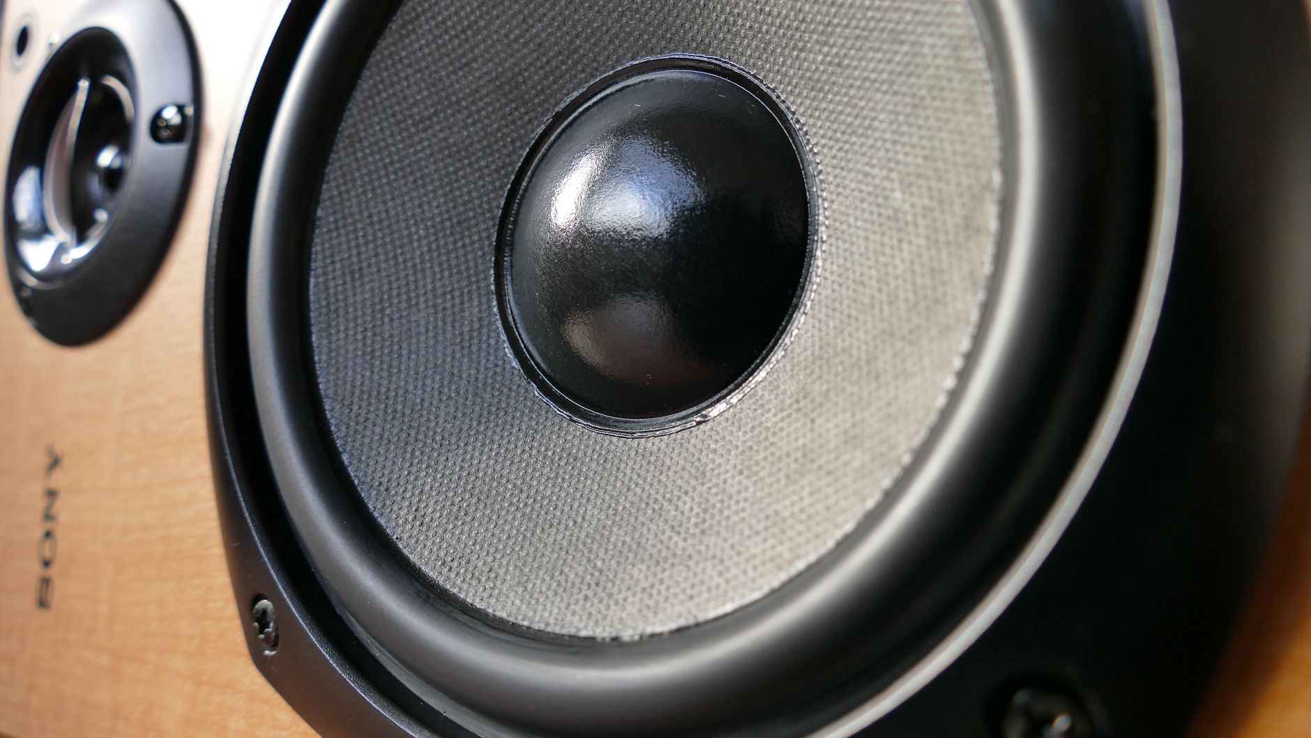 Workers handle loudspeaker components in a clean production area before a delicate coating step.