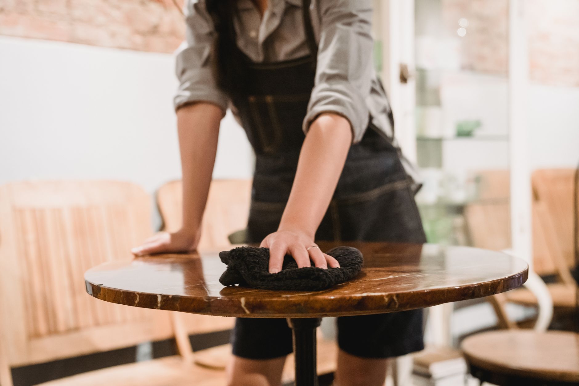 Restaurant staff cleaning and resetting tables for arriving guests.
