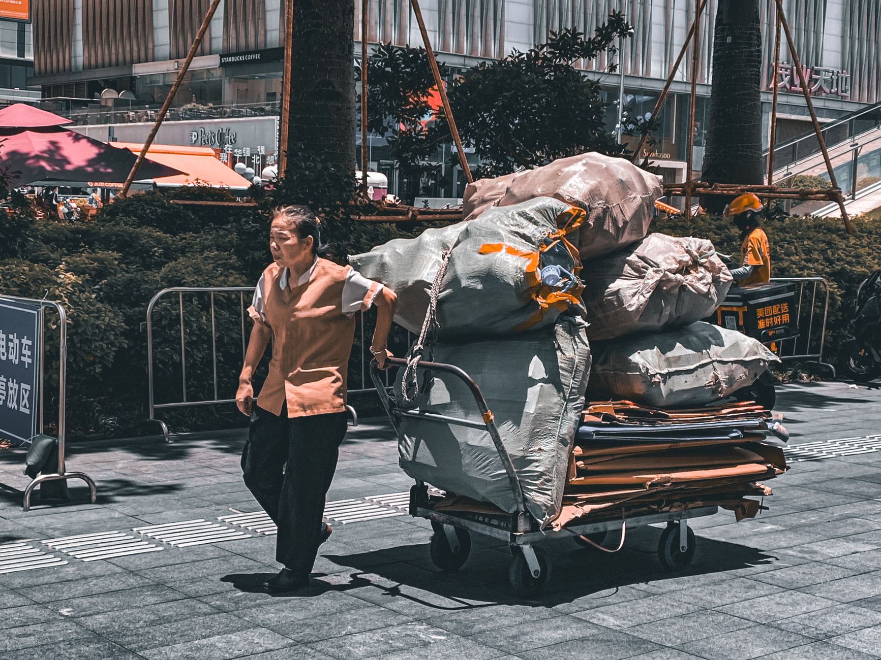 An employee pushes a heavy parts cart through an industrial aisle.