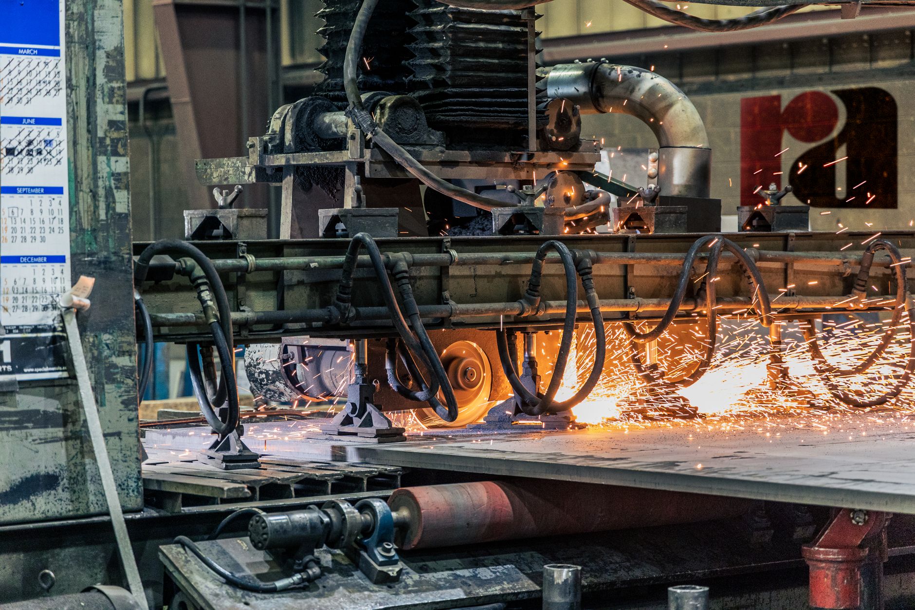 Workers and equipment occupy a metal surface finishing factory floor.