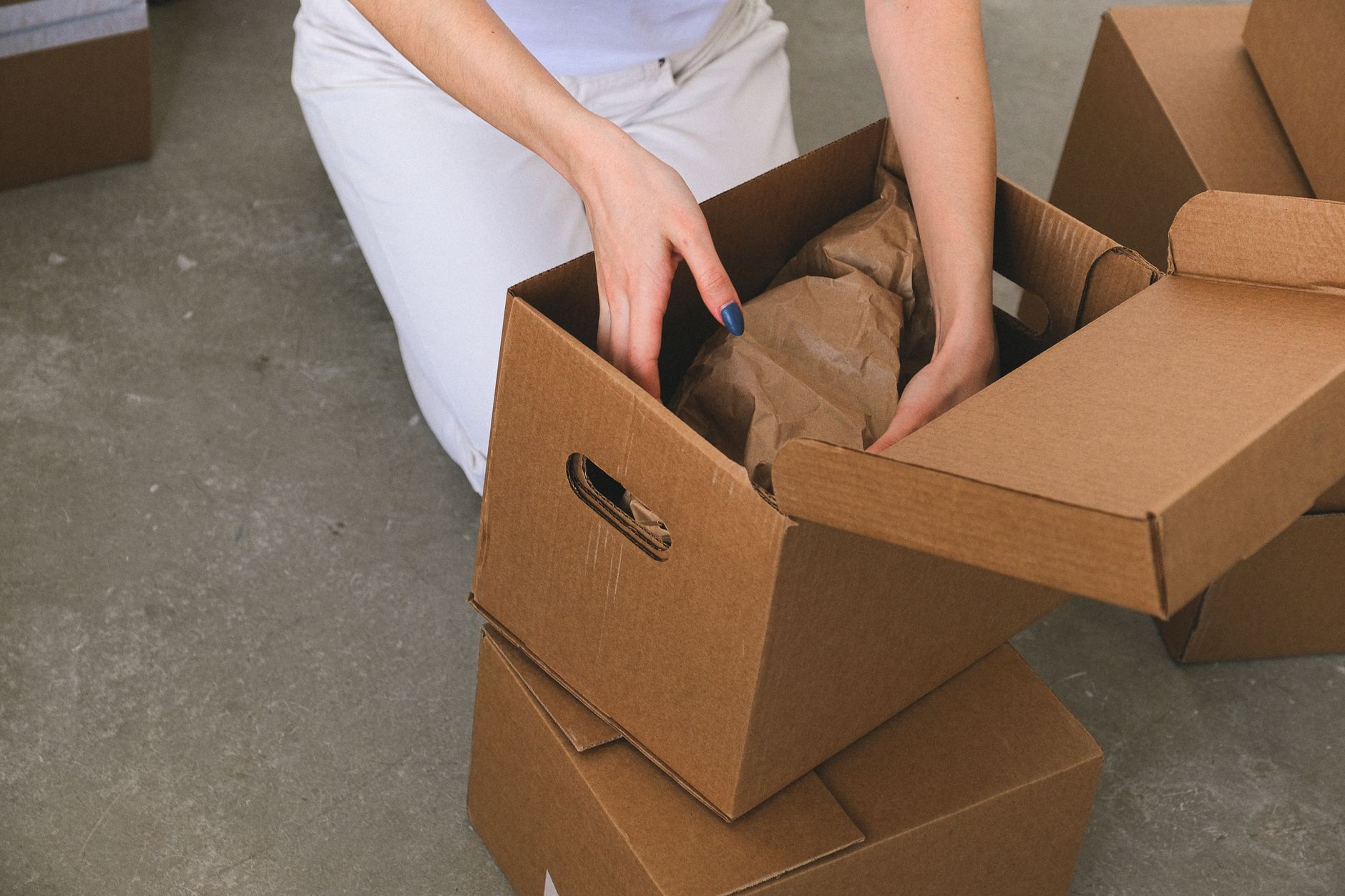 A worker prepares cardboard cartons for packing in a production workspace.