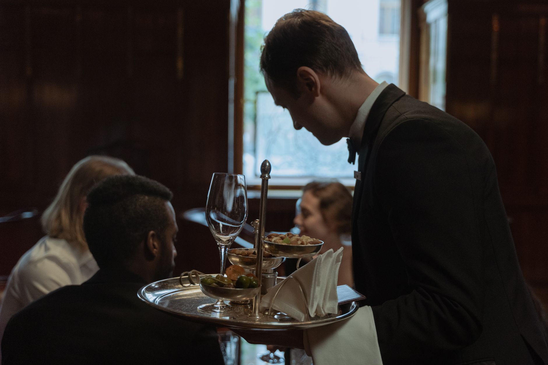 A waiter provides attentive table service to guests in a full-service restaurant.