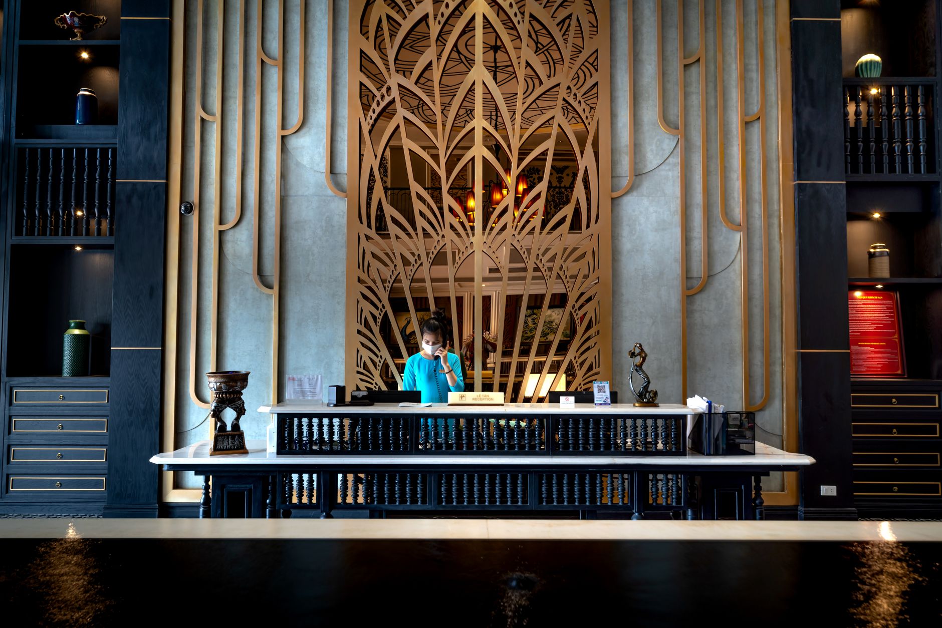 A hotel concierge assists a guest at an information desk in the lobby.
