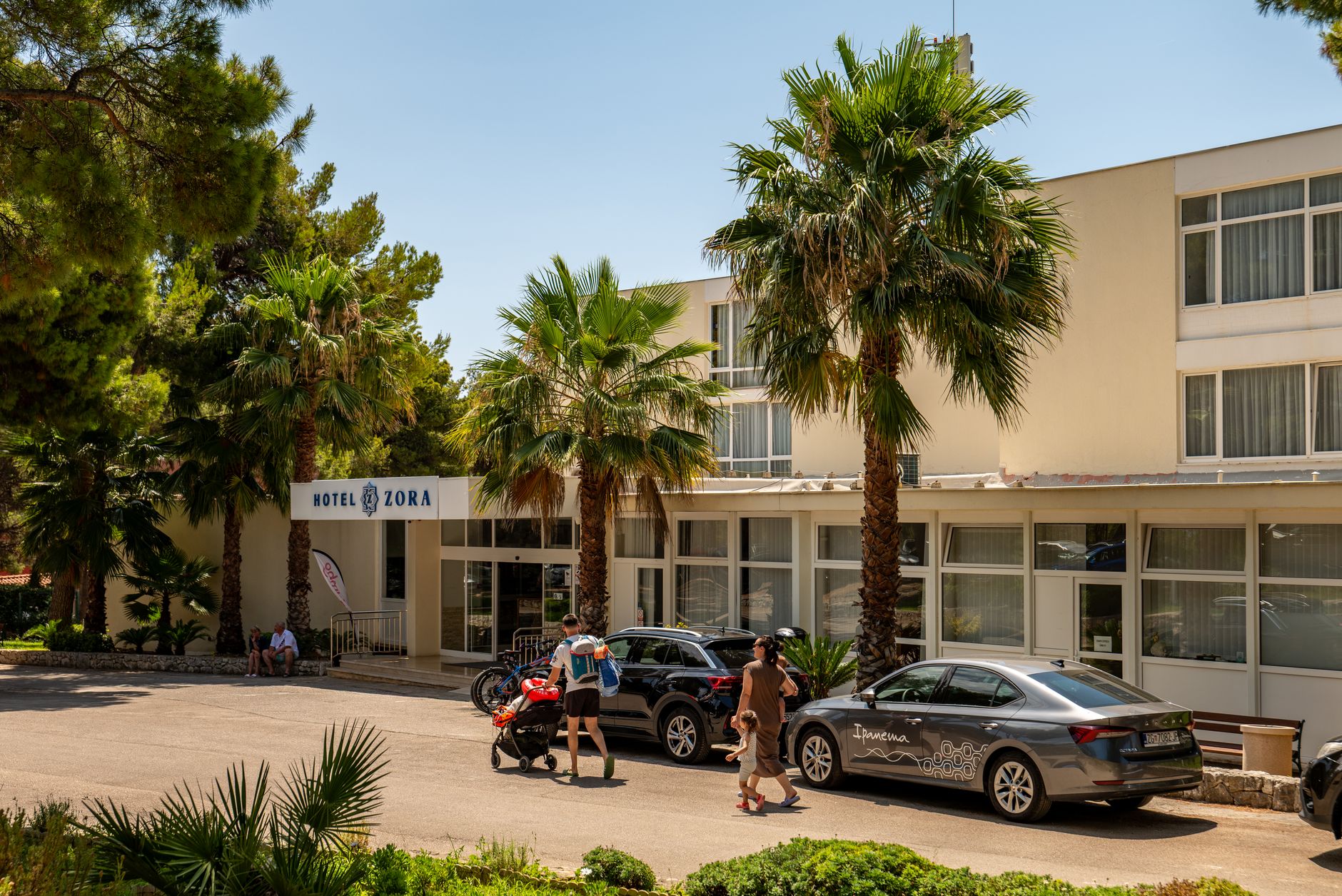 A sunlit Southern California hotel entrance welcomes arriving guests.