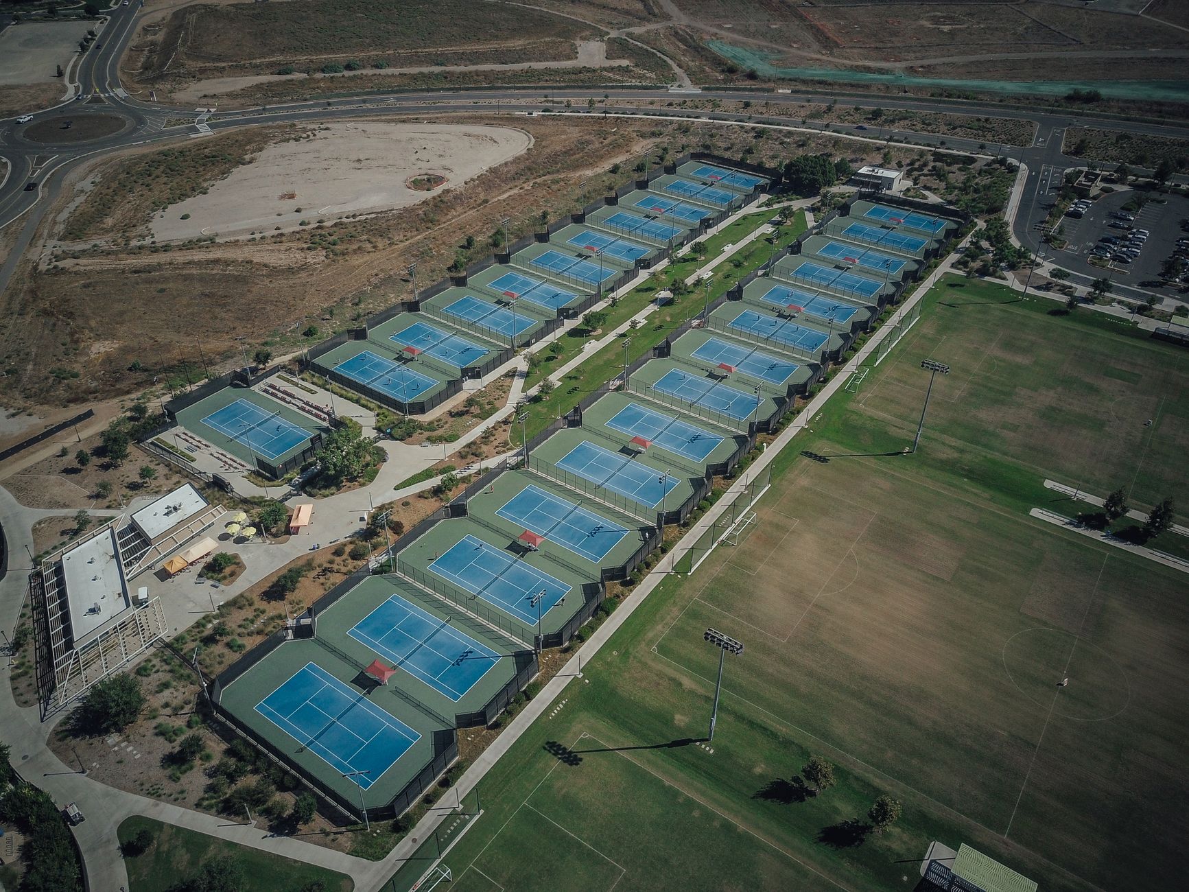 Club campus with lawns and tennis courts beside tree-lined fairways