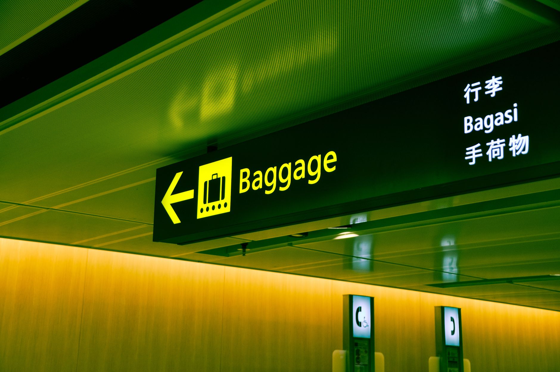 Overhead directional signs guide passengers toward airport gates, baggage claim, and terminal services.