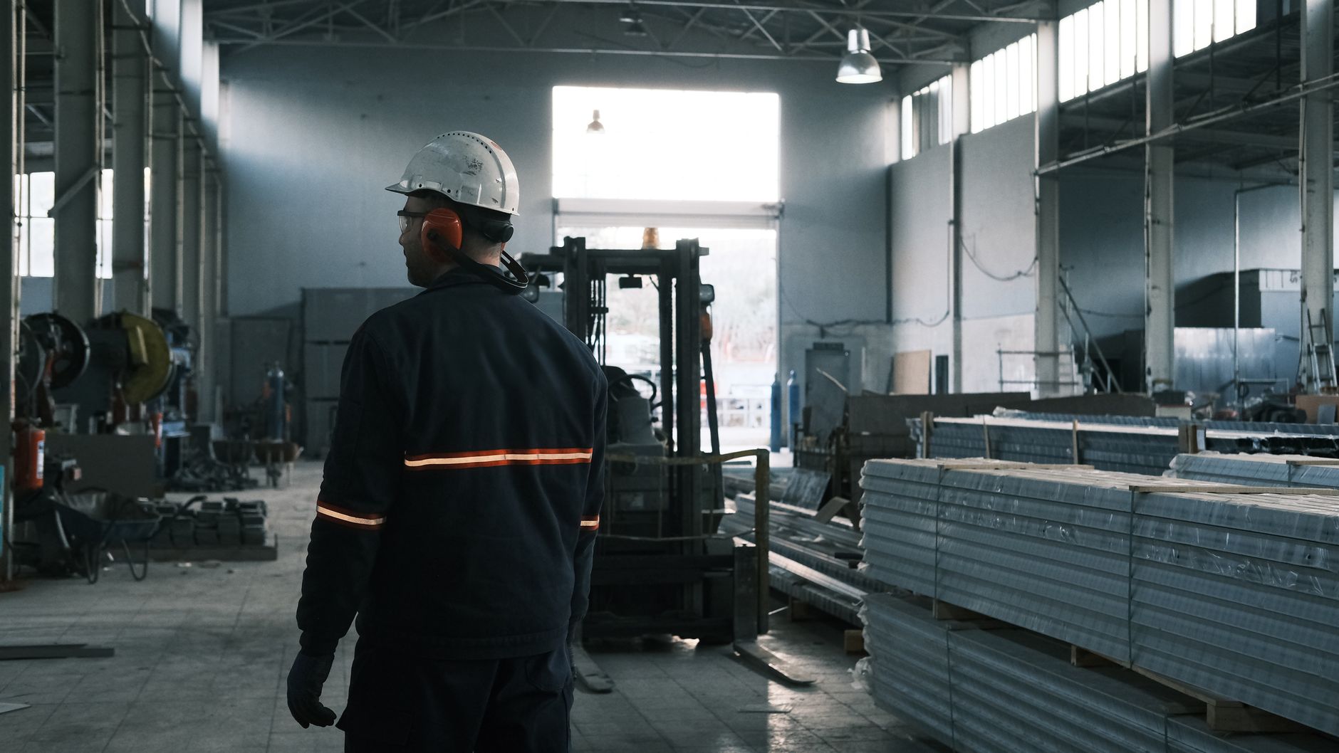 Manufacturing staff in protective gear monitoring production on an industrial floor.