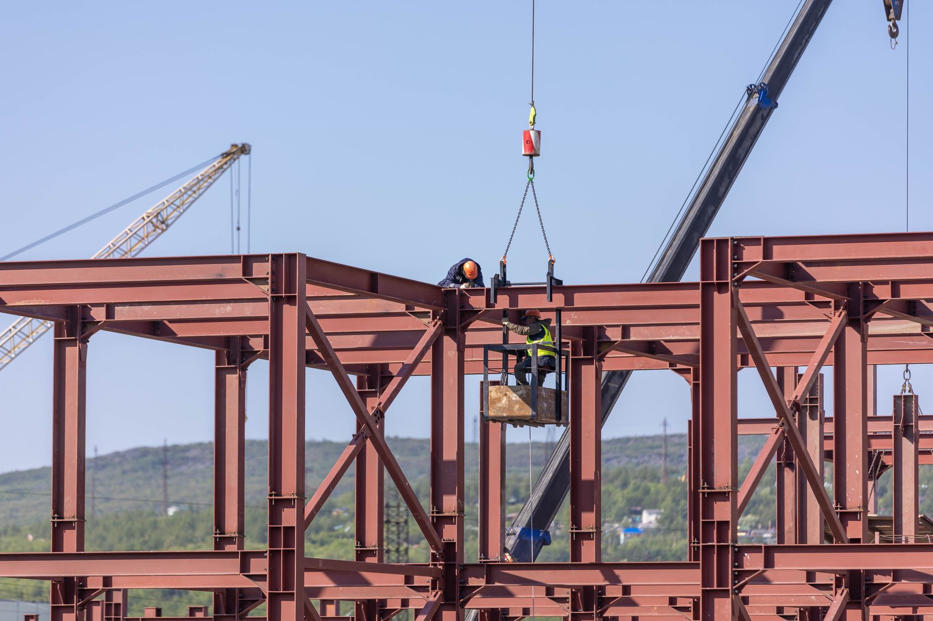 Workers handling heavy metal blanks, illustrating the ergonomic strain this forming cell removed.