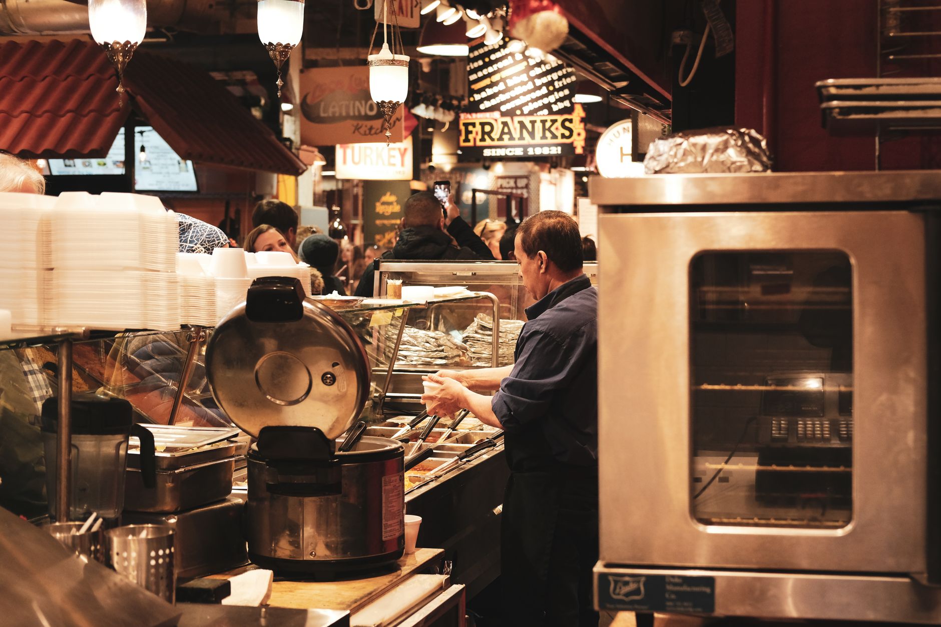 Crowded food hall with guests moving between vendor counters during peak lunch service.