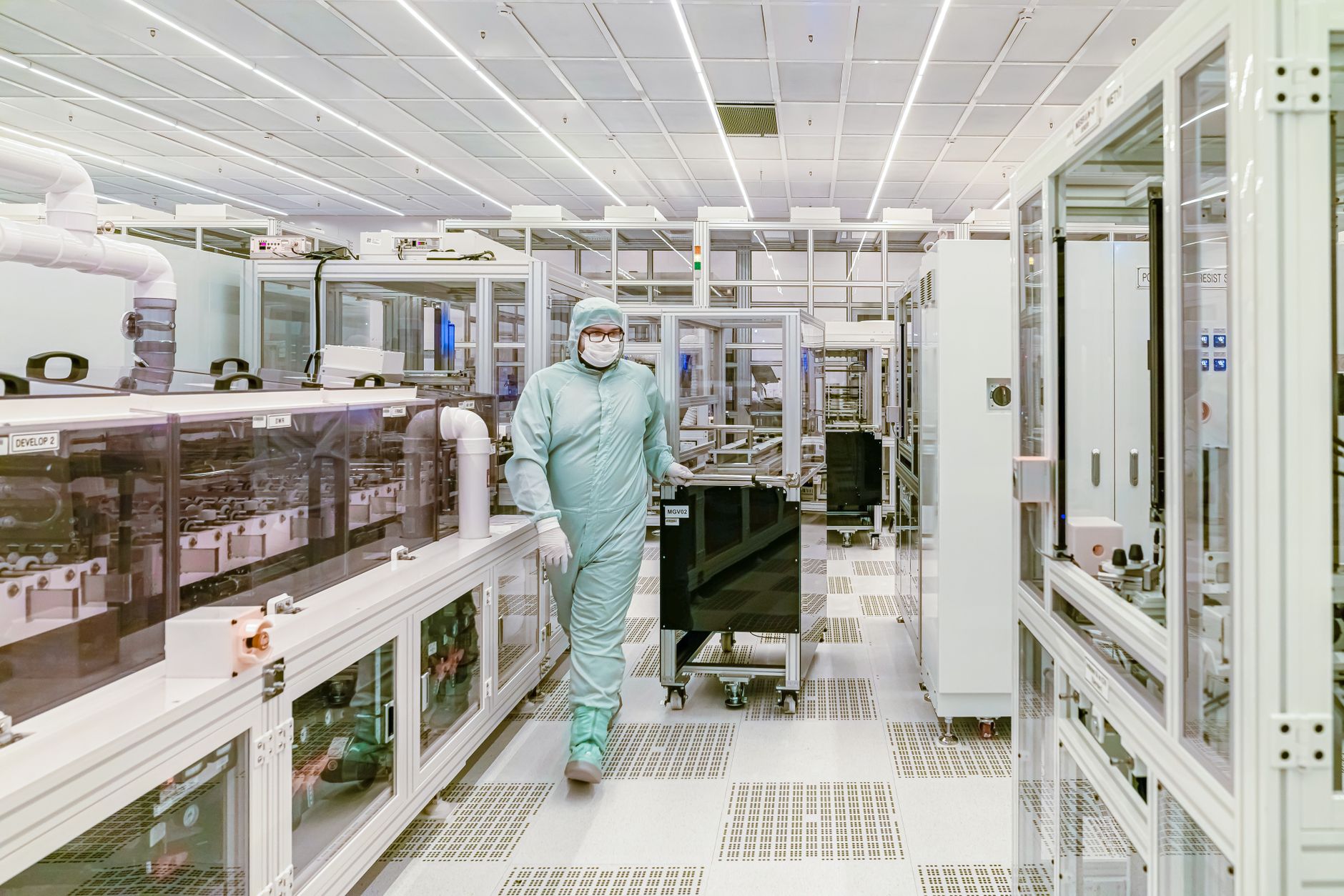 Semiconductor plant staff in cleanroom gear working near production tools instead of spending time on long internal transport walks.