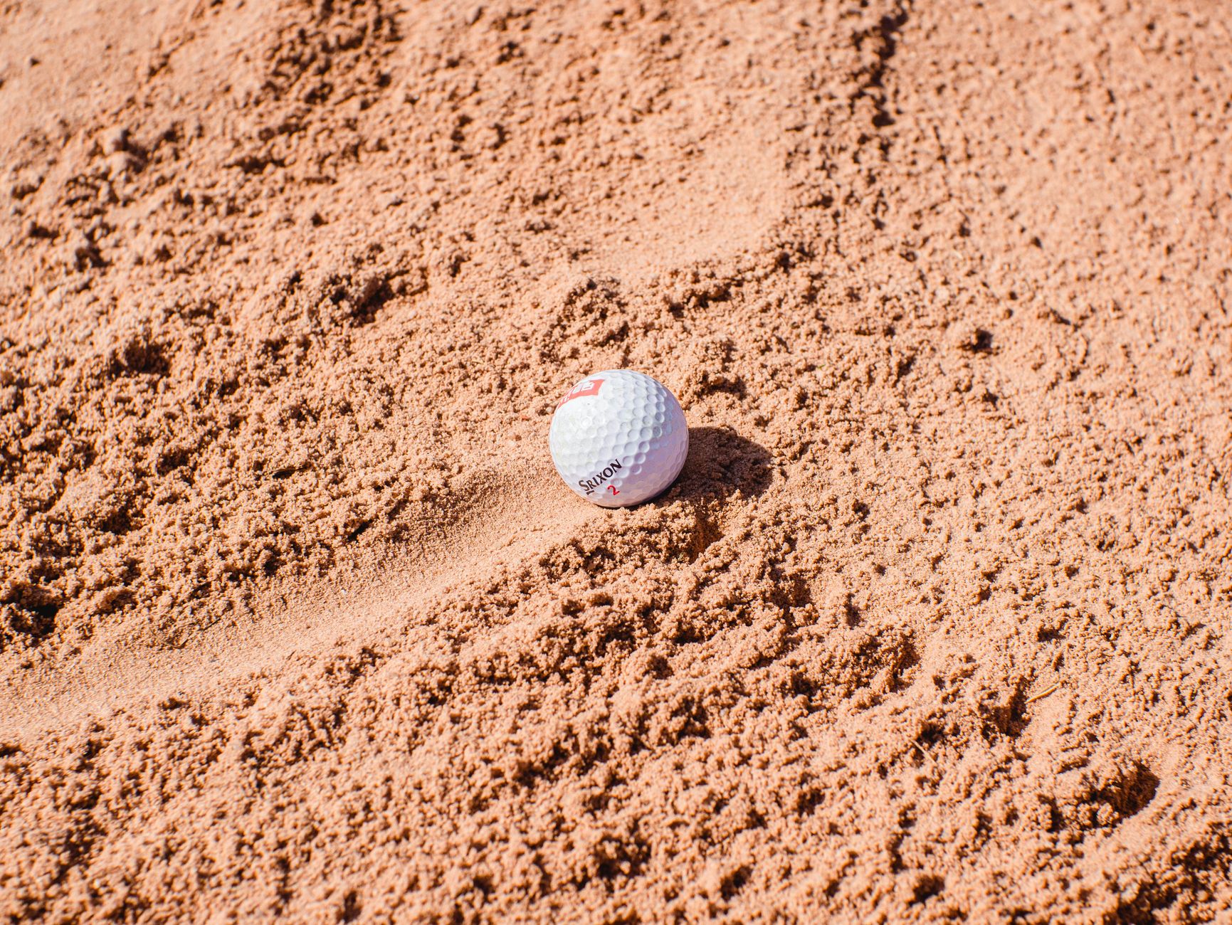 Detail work at a bunker lip with fairway grass in the background.