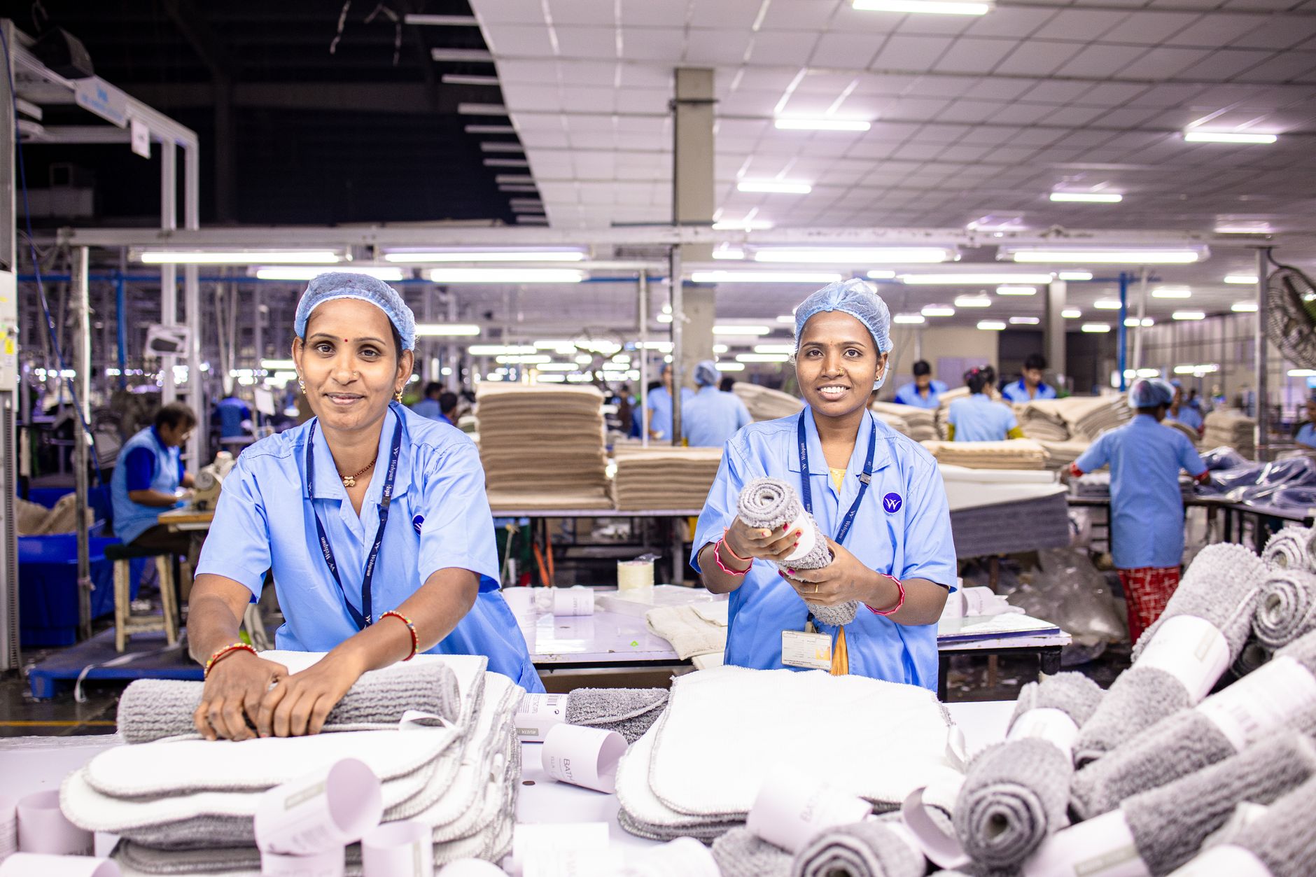 Employees work across assembly stations on a busy manufacturing floor.