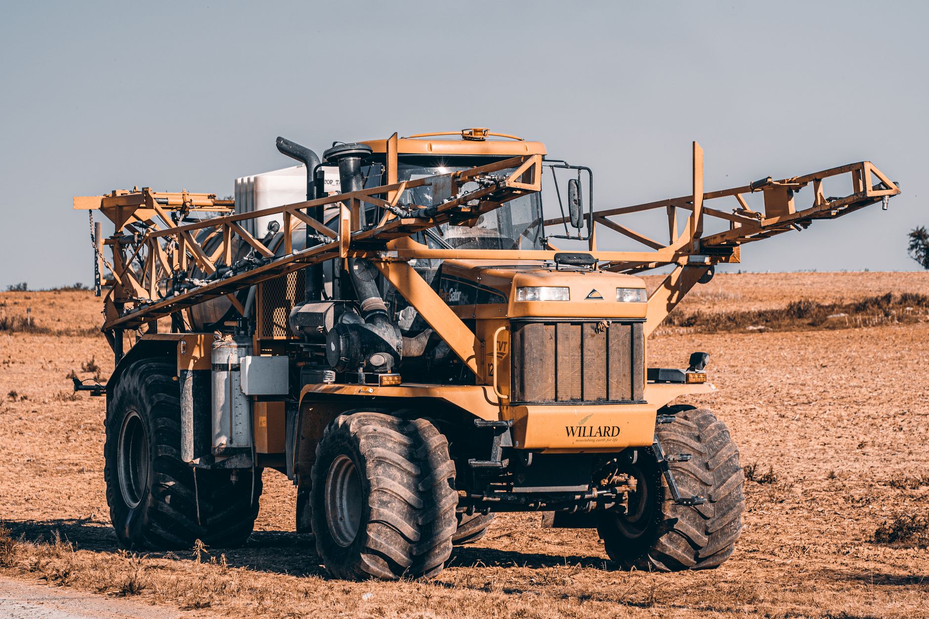 A farm sprayer moving along rows in a vegetable field during crop care.
