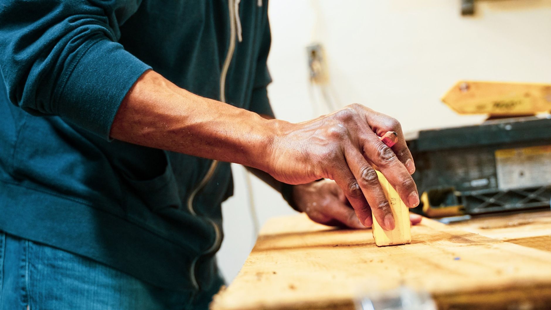 A woodworker inspects the smooth finish and edges of a completed wooden board.