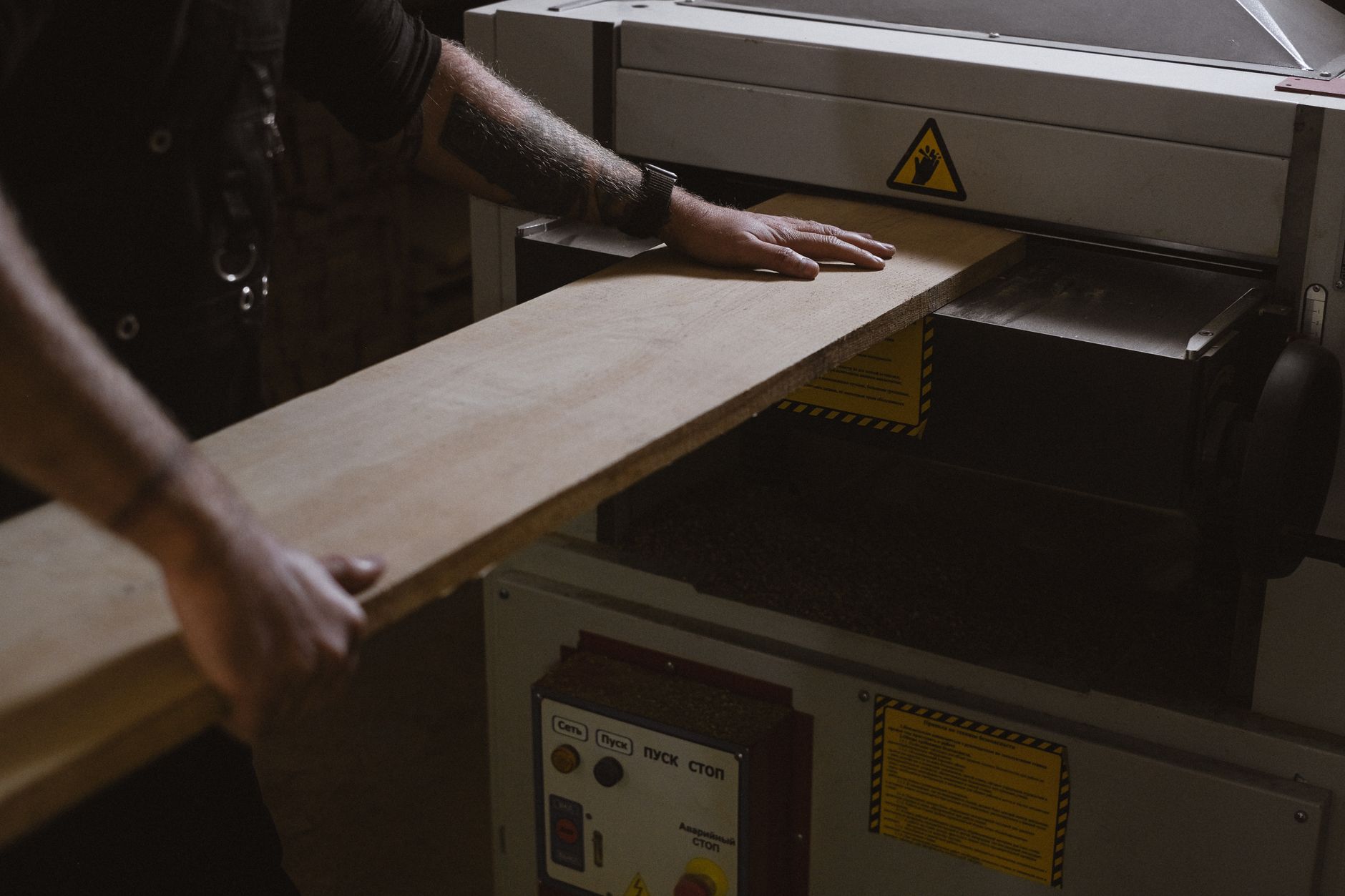 A craftsperson hand-sands a wooden cutting board at a workshop bench.