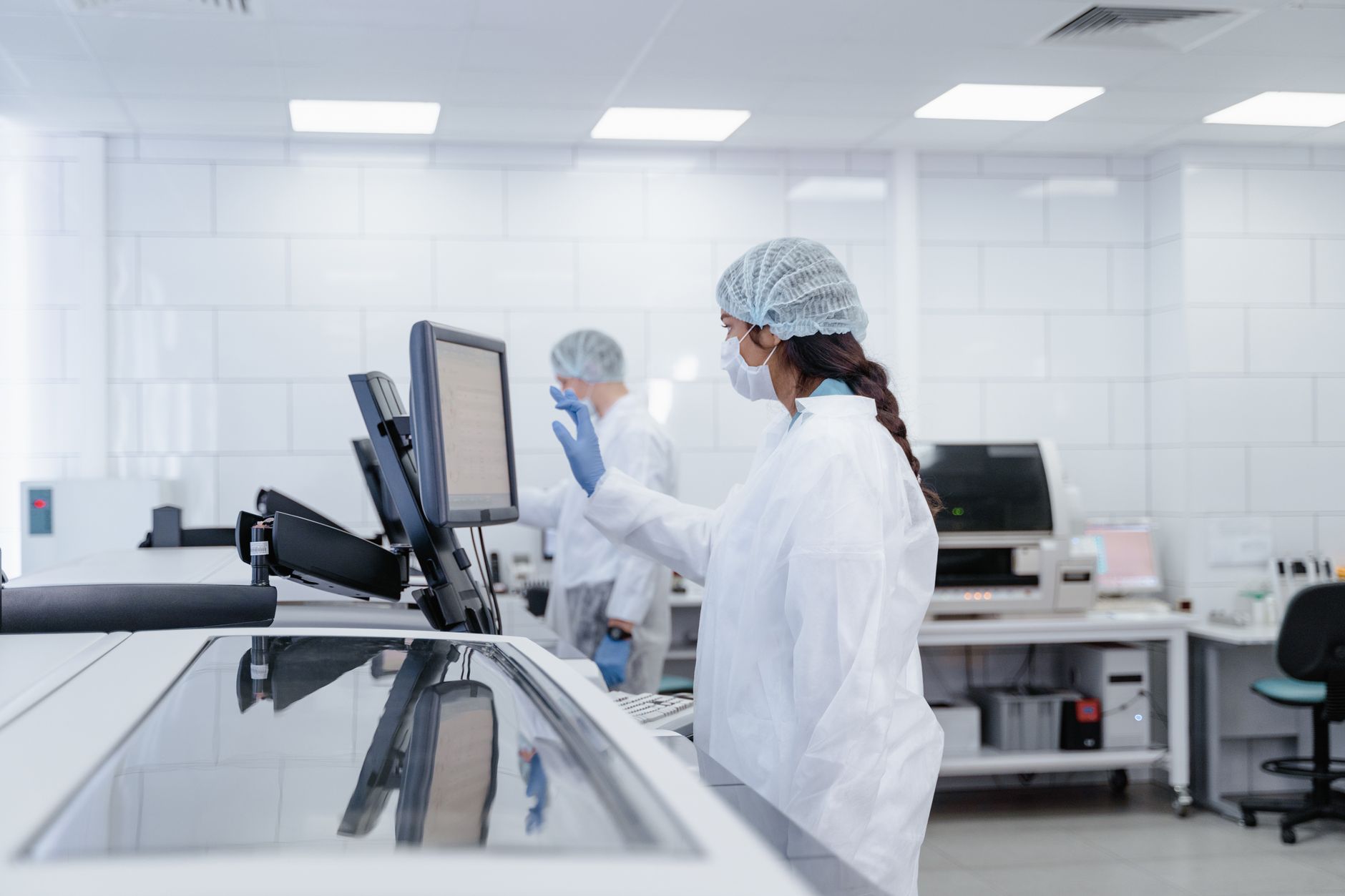 A hospital pharmacy professional preparing sterile IV medication in a clean clinical workspace.